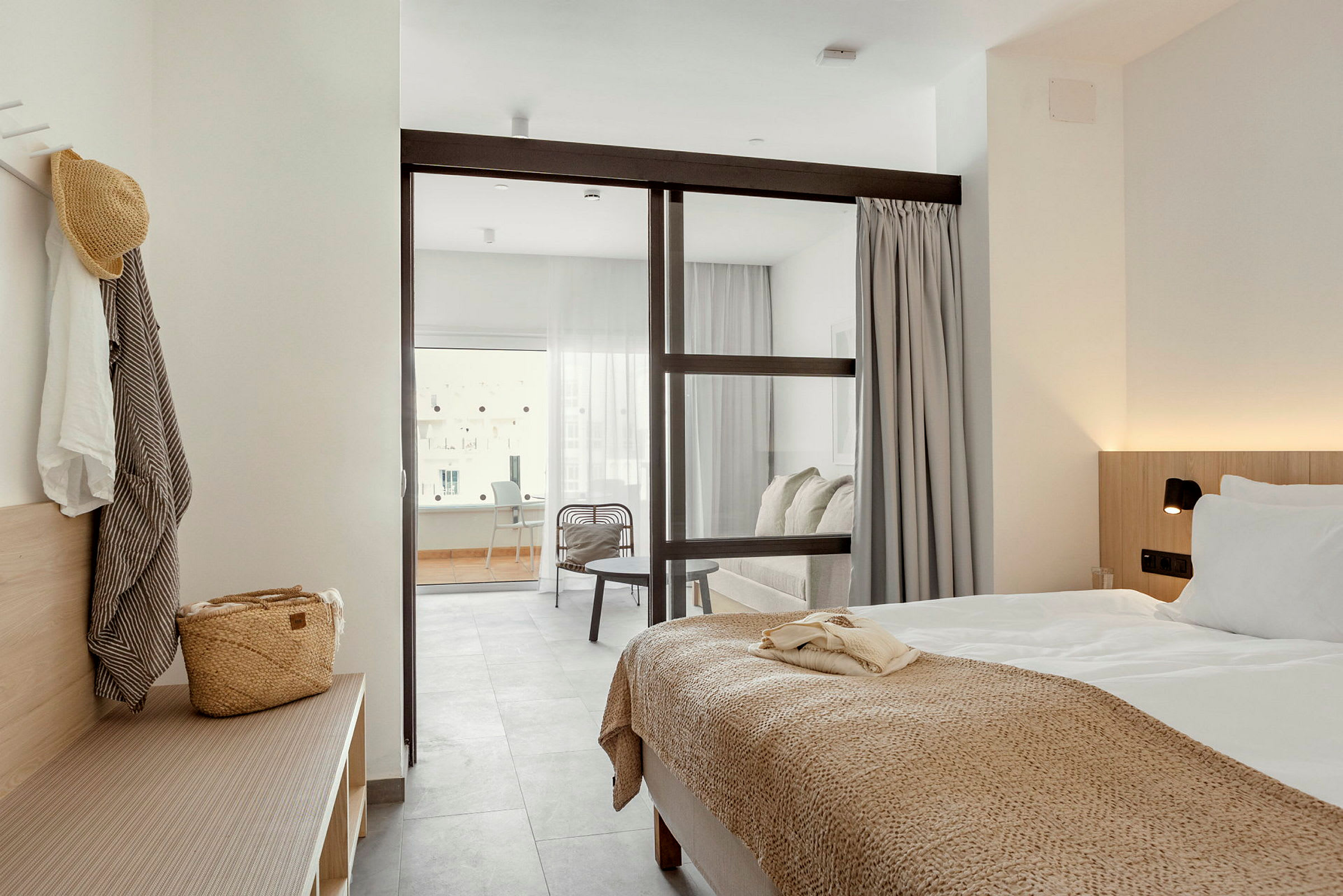 Hotellihuone, jossa sänky ja istuinryhmä lasiseinällä erotettuna. (Tekoälyn luoma teksti)