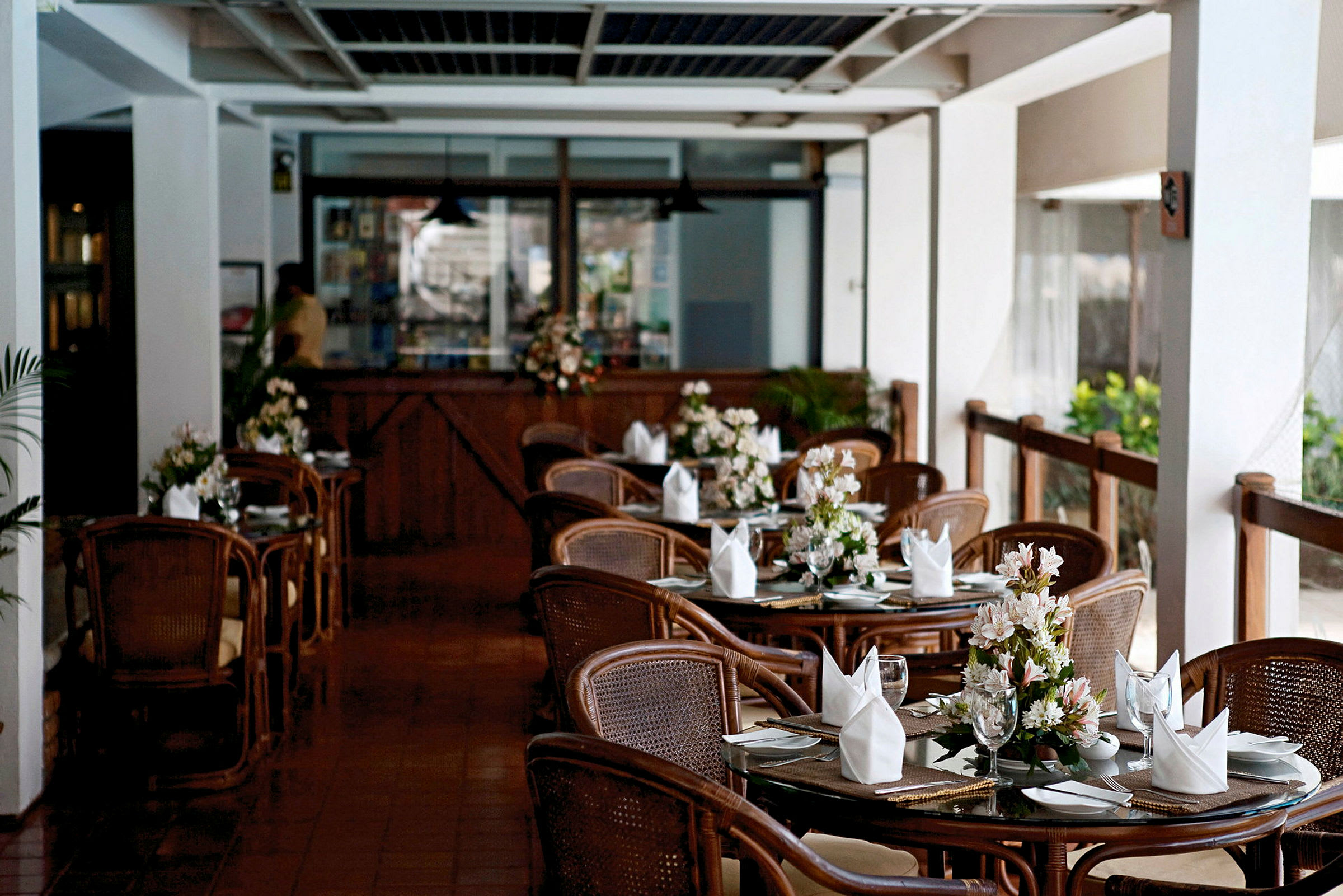 Ravintola, jossa pöydät on katettu, ja jokaisessa pöydässä on kukkia. (Tekoälyn luoma teksti)