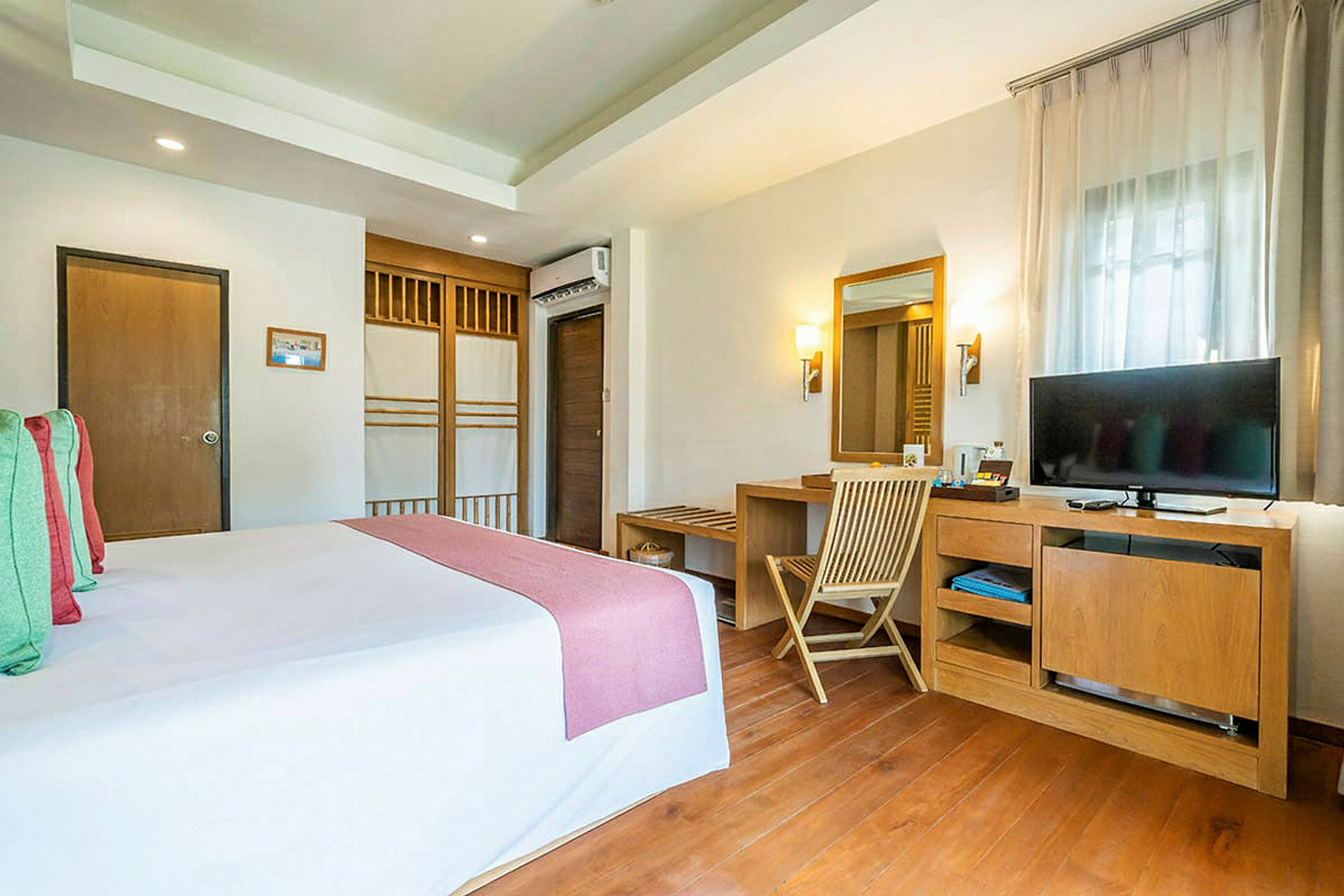 Kuva hotellihuoneesta, jossa on pedattu sänky ja kirjoituspöytä peilin ja television kera. (Tekoälyn luoma teksti)