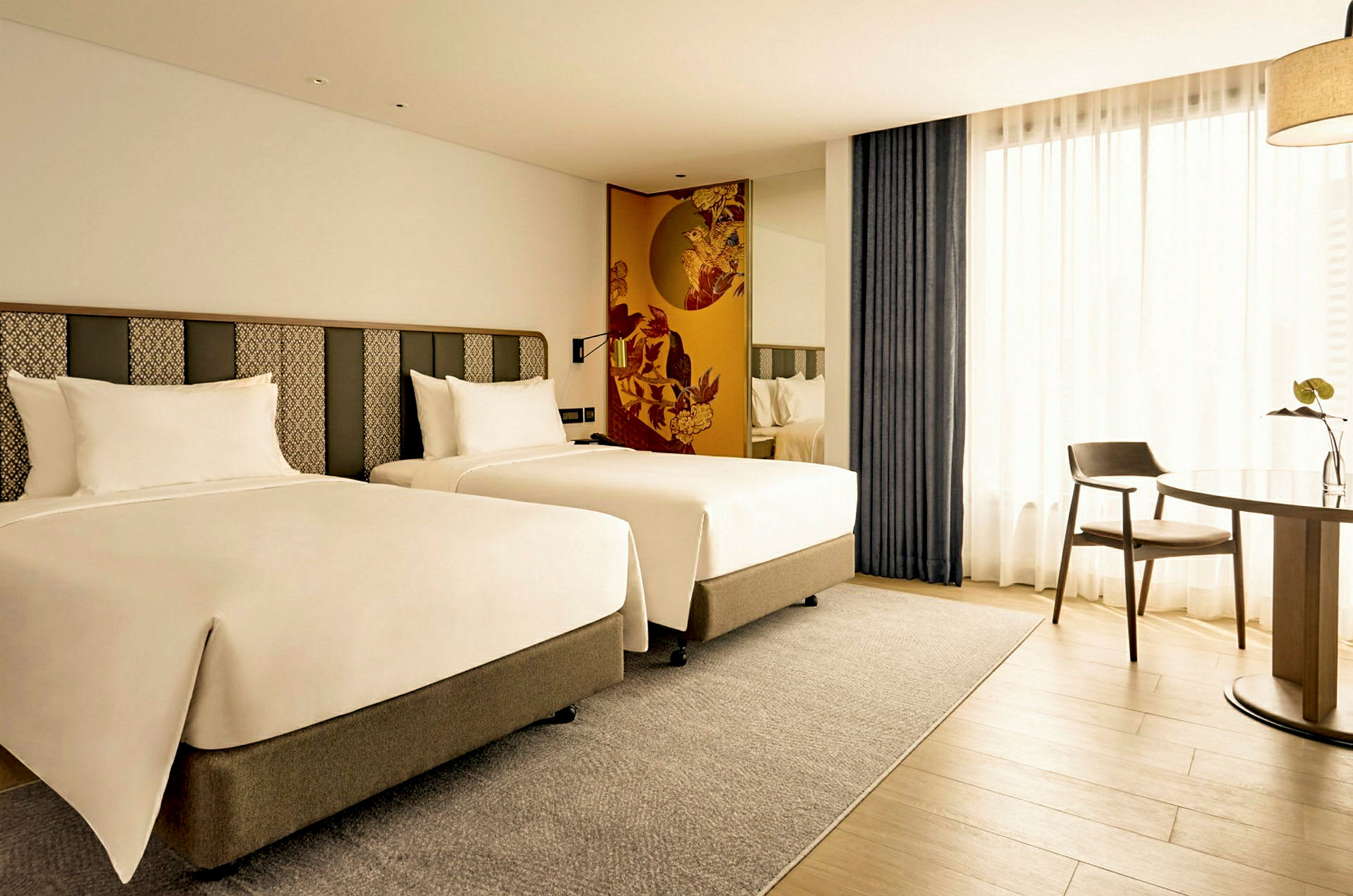 Hotellihuone, jossa on kaksi erillistä sänkyä ja pöytä tuoleilla. (Tekoälyn luoma teksti)