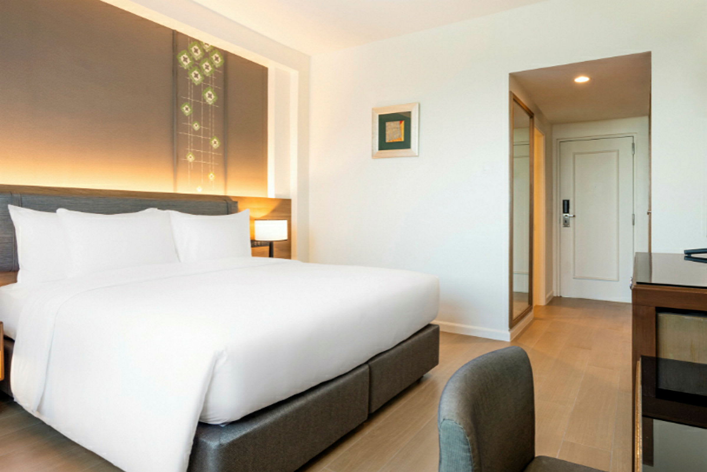 Moderni hotellihuone, jossa iso sänky, valkoiset lakanat ja pääty, jossa on sisäänrakennettu valaistus. (Tekoälyn luoma teksti)