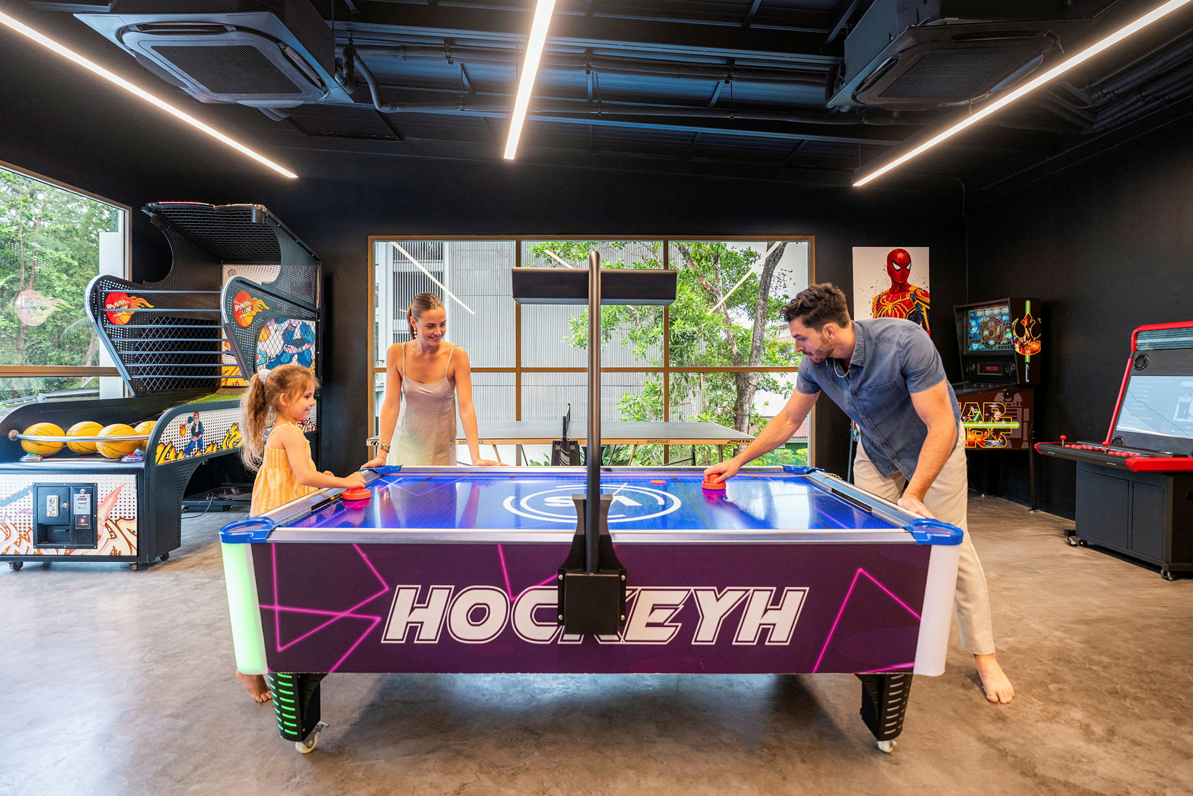 Ilmakiekkopöytä viihdehuoneessa, jossa ympärillä arcade-pelikoneita. (Tekoälyn luoma teksti)