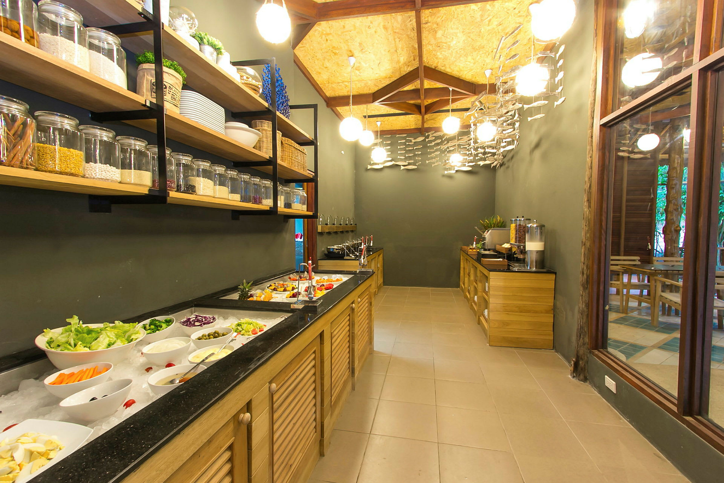 Buffet, jossa on salaattia ja lisukkeita vasemmalla sekä moderni sisustus puuelementeillä. (Tekoälyn luoma teksti)