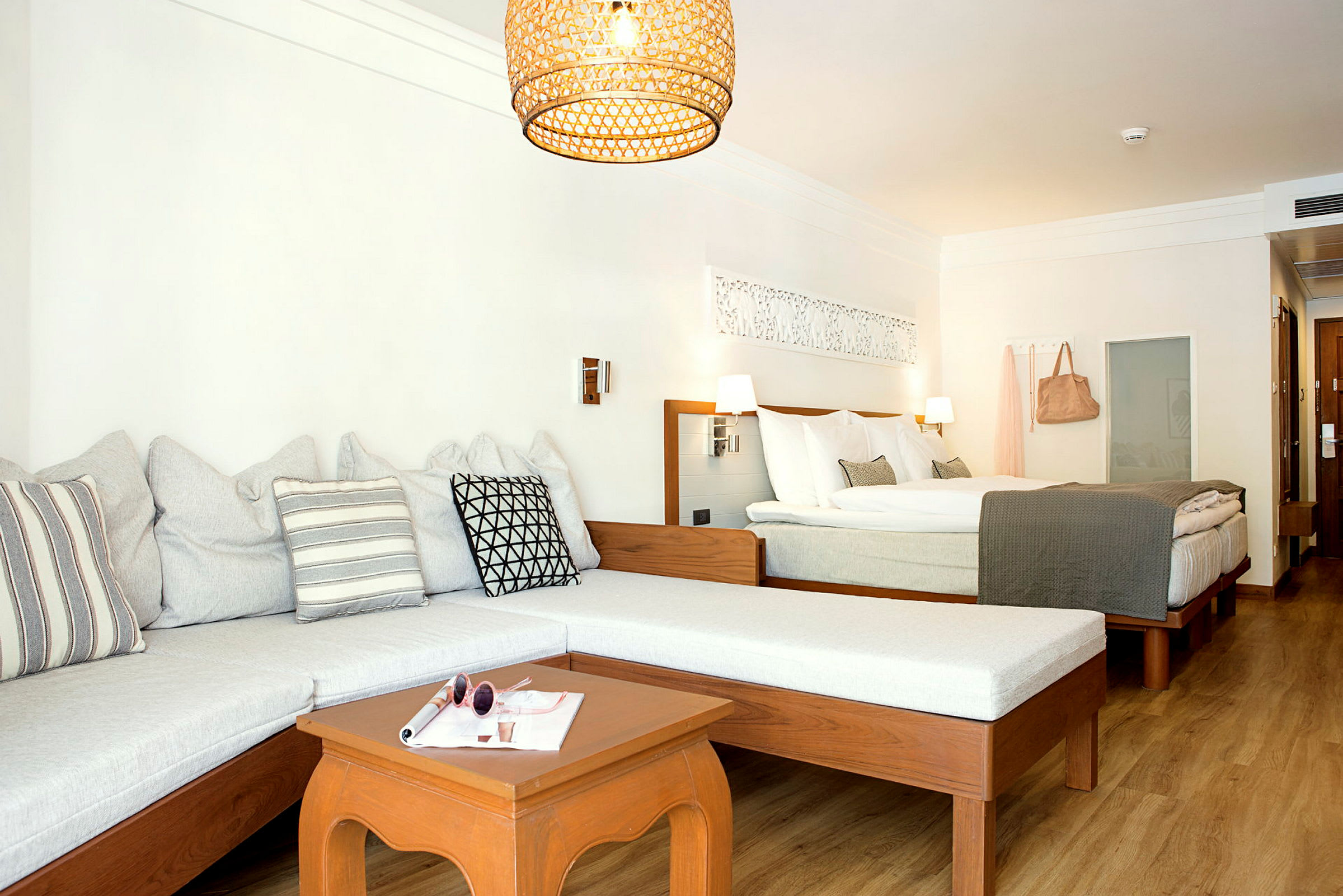 Hotellihuone, jossa on sohva, pöytä ja parisänky. (Tekoälyn luoma teksti)