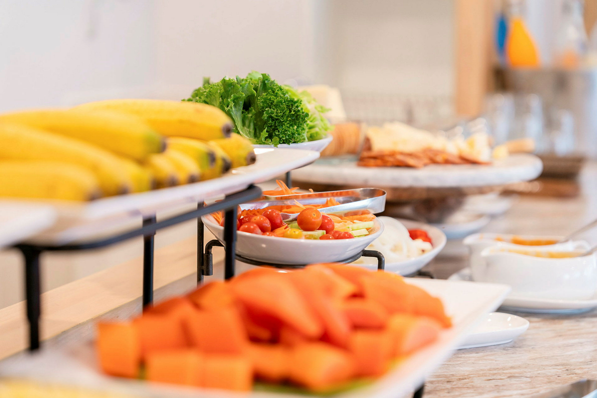 Buffet, jossa on hedelmiä, vihanneksia ja lisukkeita tarjottimilla. (Tekoälyn luoma teksti)