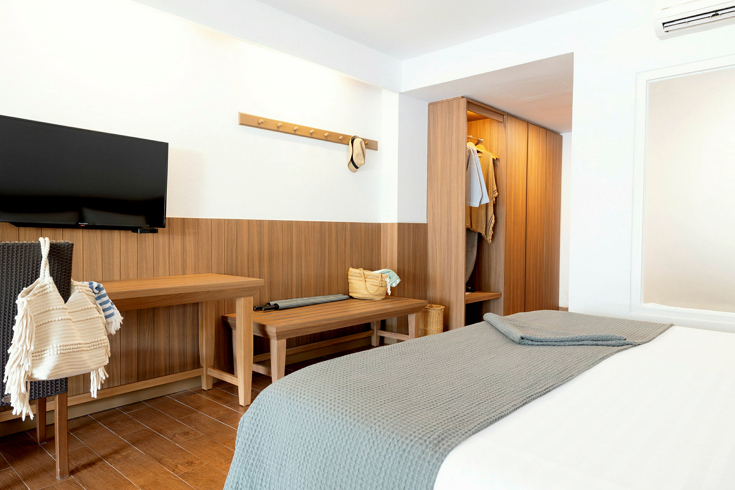 Hotellihuone, jossa on sänky, vaatekaappi ja seinällä televisio. (Tekoälyn luoma teksti)