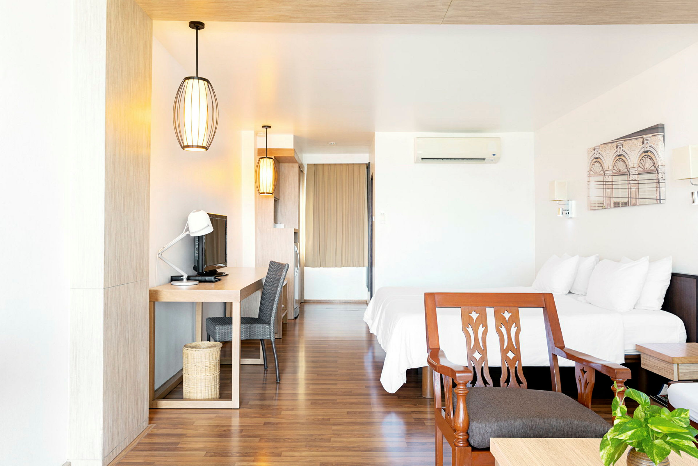 Hotellihuone, jossa on parivuode, kirjoituspöytä, televisio ja tuoli. (Tekoälyn luoma teksti)
