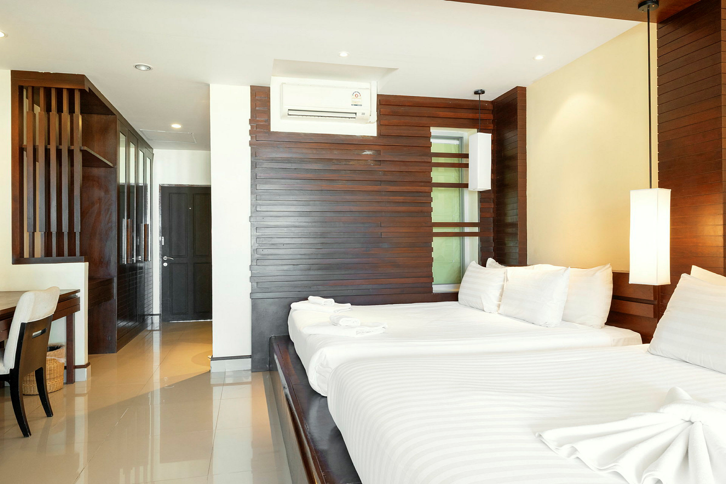 Moderni hotellihuone, jossa on suuri sänky, puiset seinäpaneelit ja mukavat vuodevaatteet. (Tekoälyn luoma teksti)