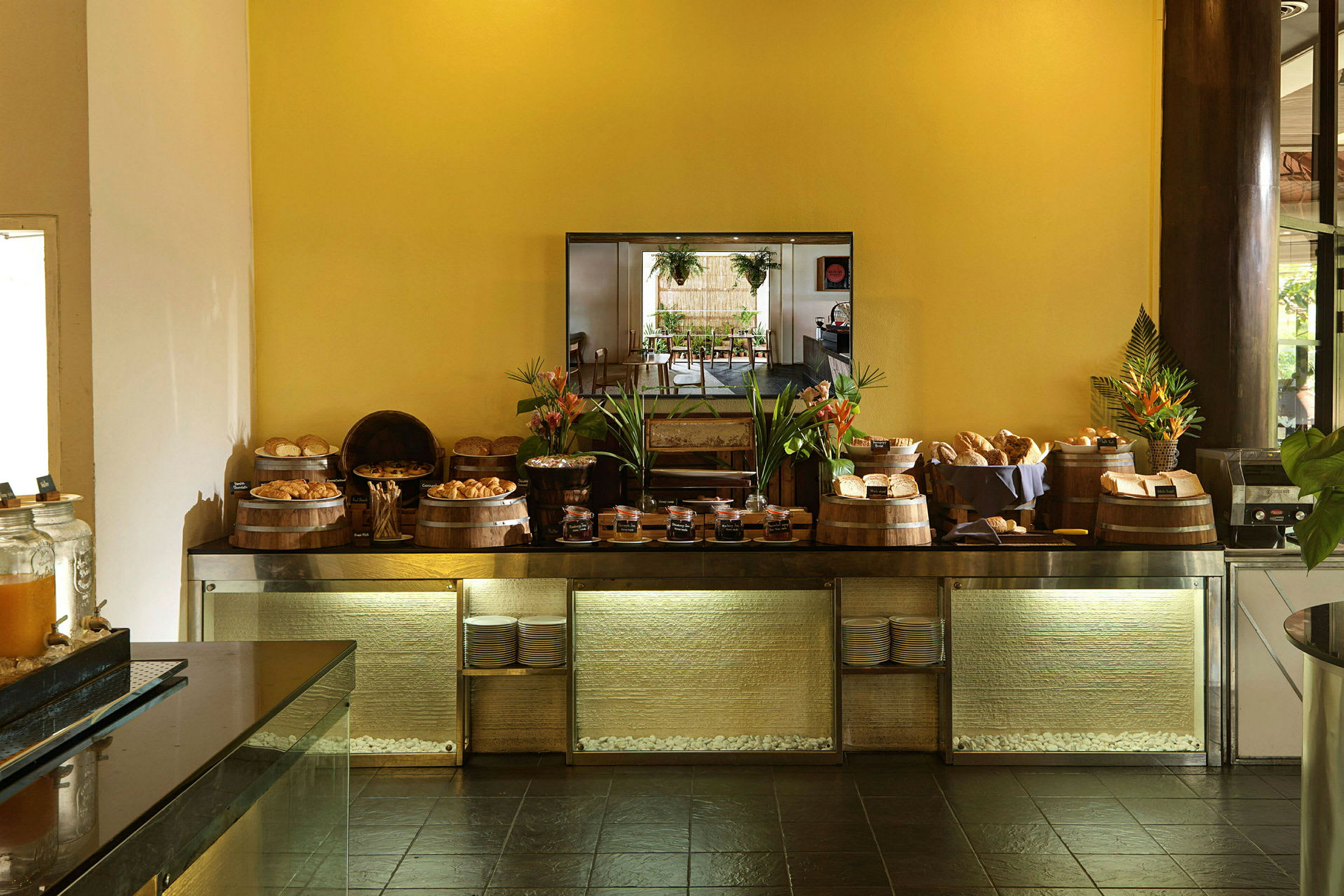 Buffet, jossa on leipää ja levitteitä, koristeltuna kasveilla, esillä pöydällä. (Tekoälyn luoma teksti)