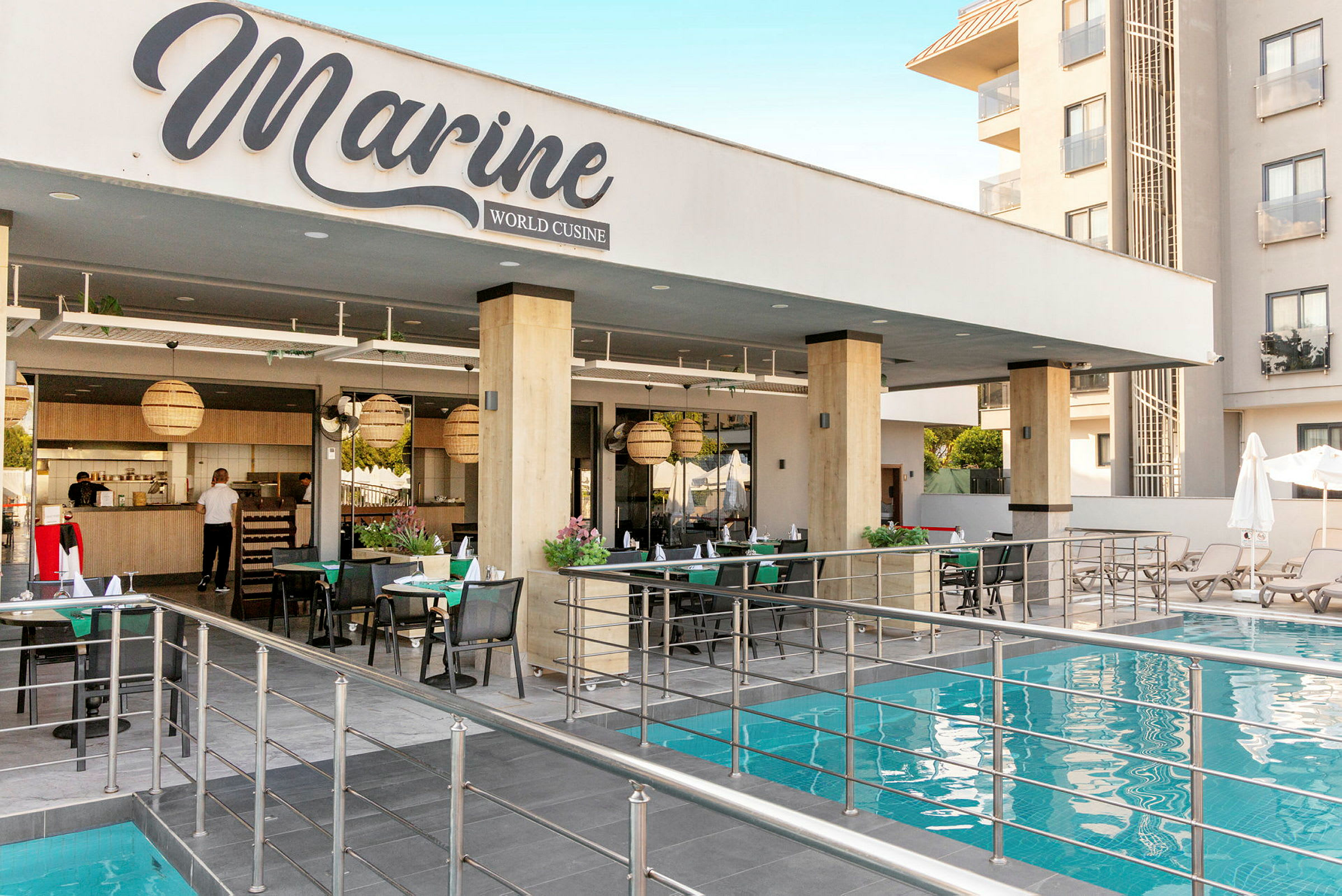 Ravintola nimeltä Marine World Cuisine sijaitsee uima-altaan vieressä, jossa on istumapaikkoja ja pöytiä. (Tekoälyn luoma teksti)