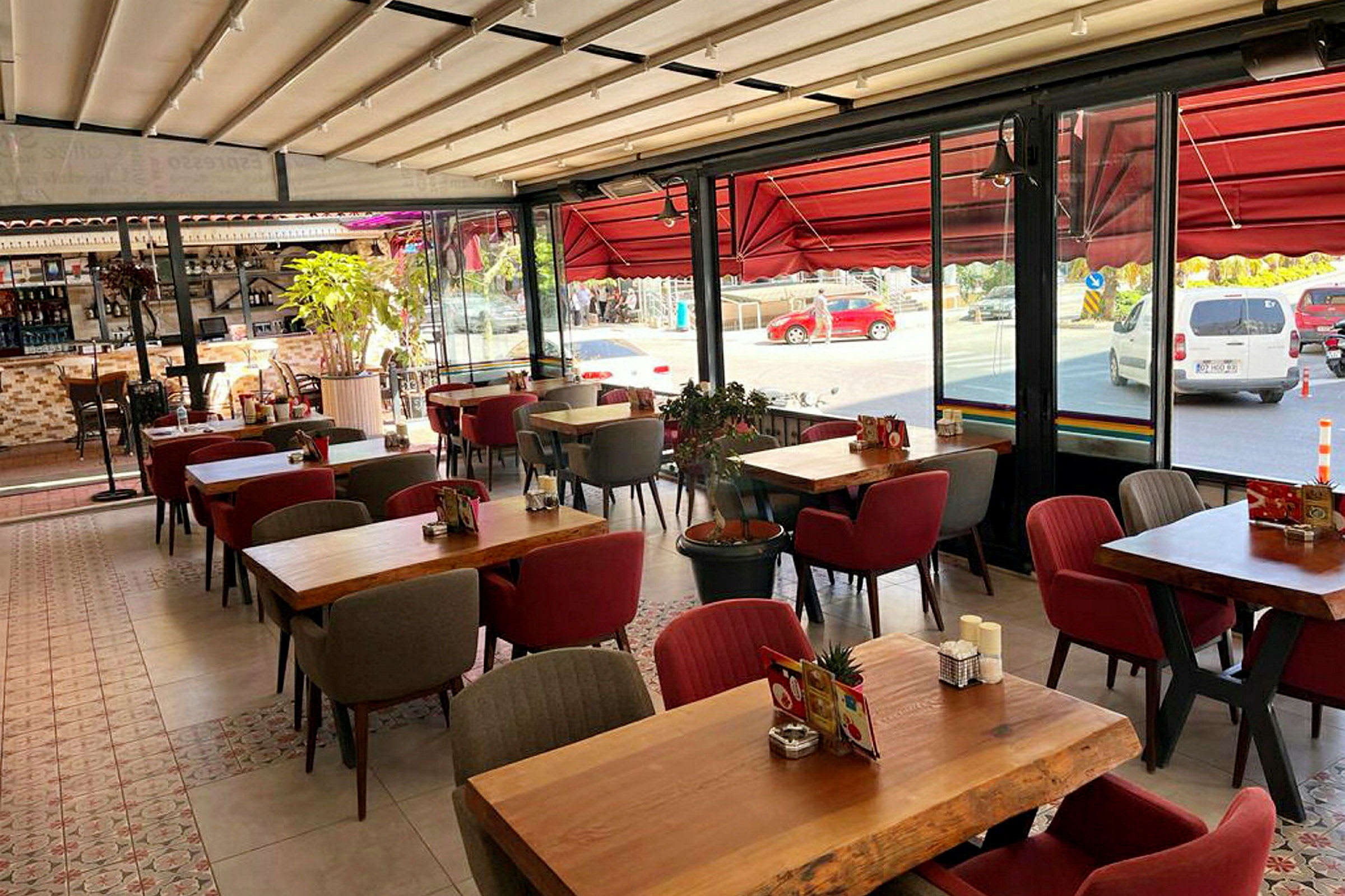Ravintola, jossa on pöytiä ja tuoleja sekä suuret ikkunat kadulle. (Tekoälyn luoma teksti)