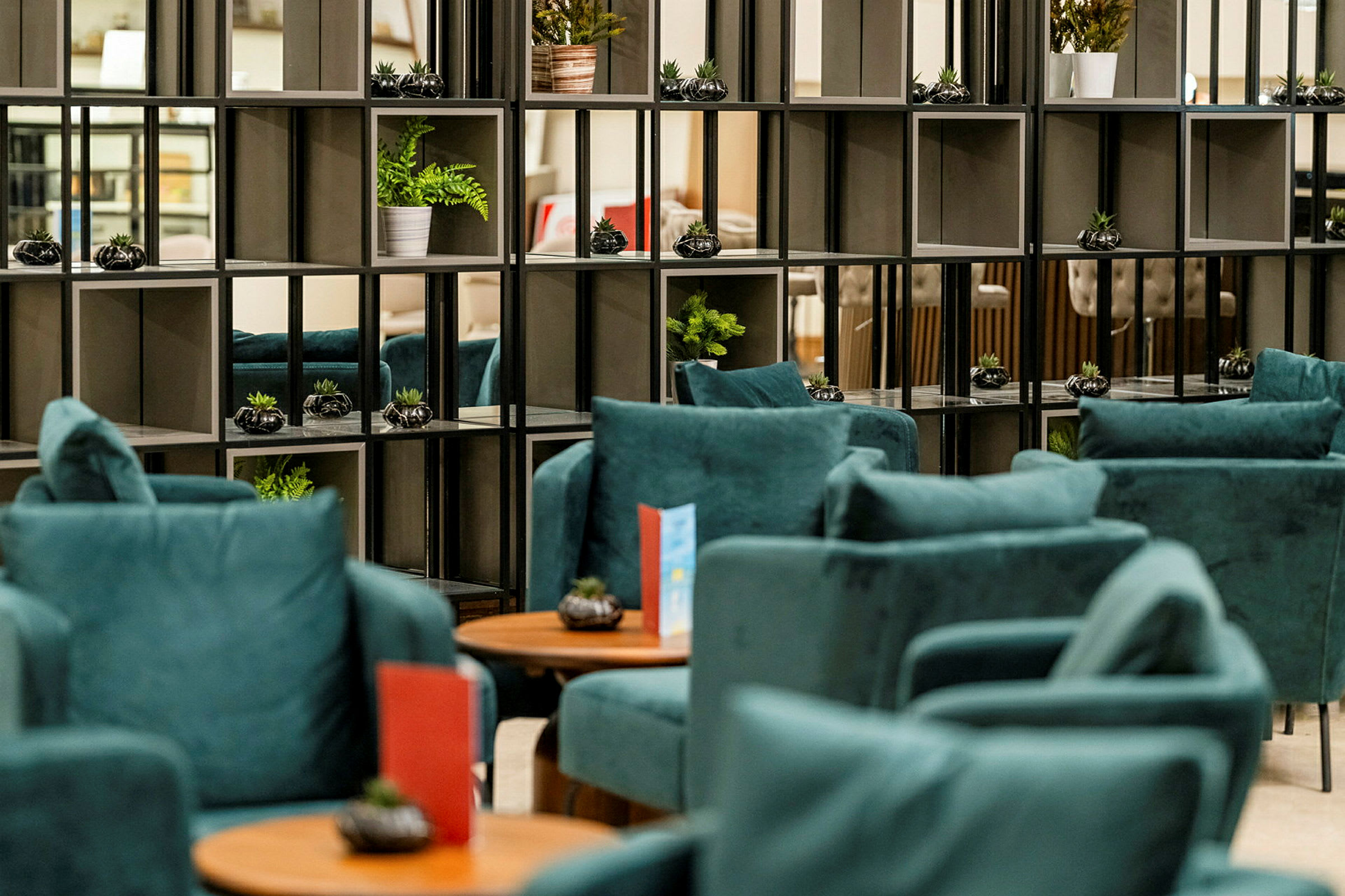 Lounge, jossa on sinisiä nojatuoleja ja hyllyjä koristekasveilla. (Tekoälyn luoma teksti)