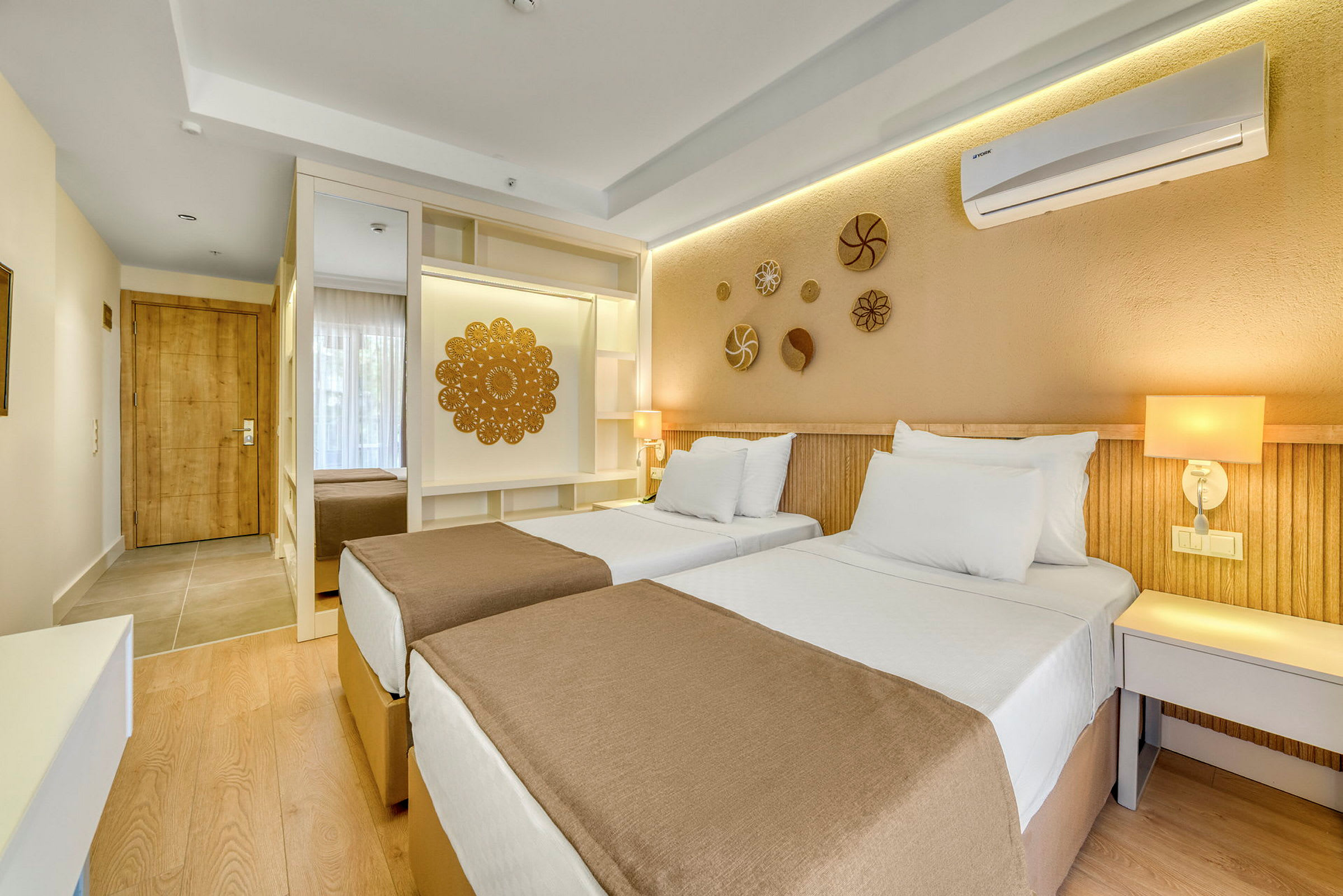 Hotellihuone kahdella yhden hengen sängyllä, sisustettu moderneilla yksityiskohdilla ja beigellä sävyllä. (Tekoälyn luoma teksti)