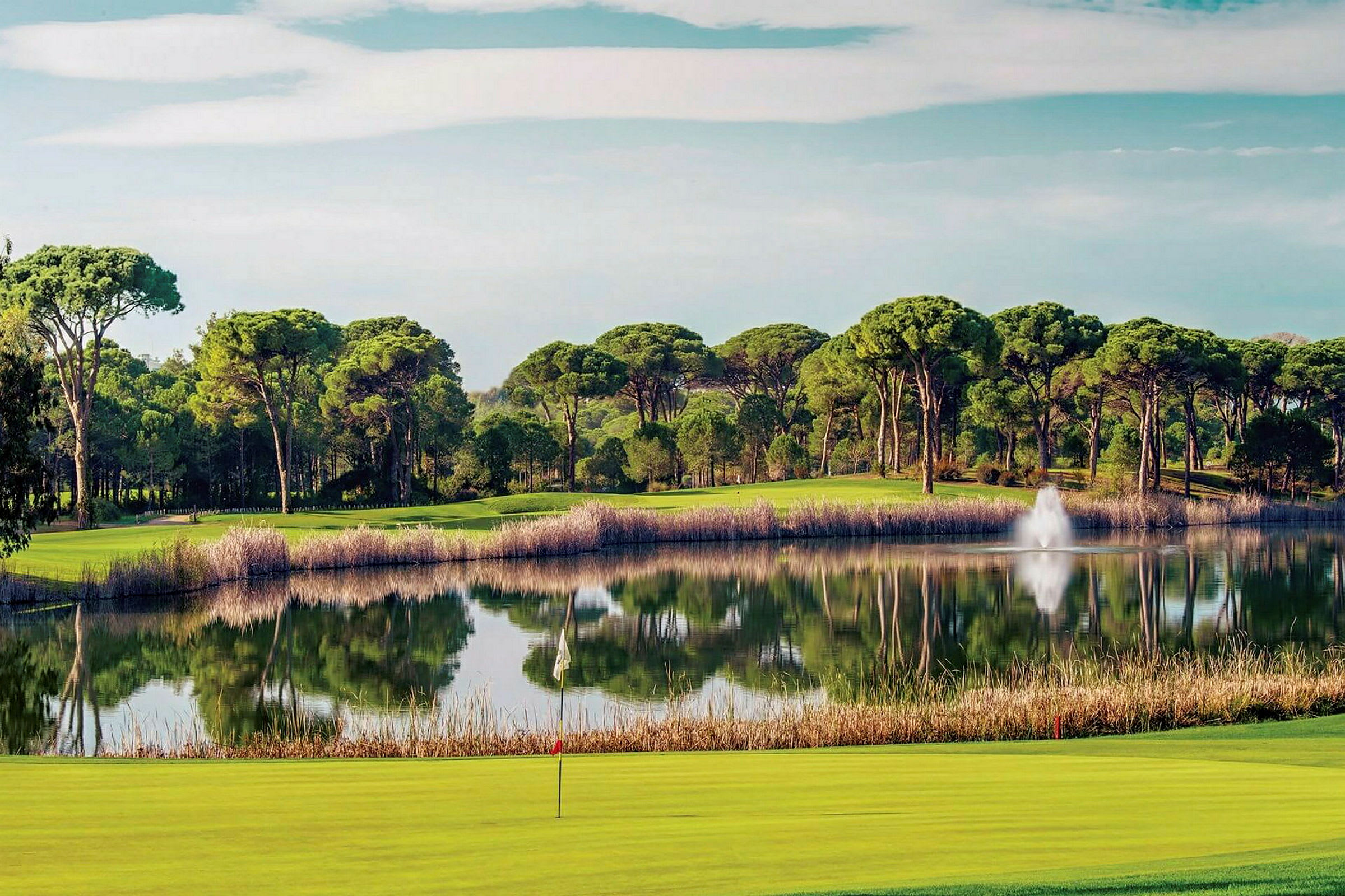 Näkymä järvelle, jota ympäröivät puut, etualalla golfkenttä. (Tekoälyn luoma teksti)