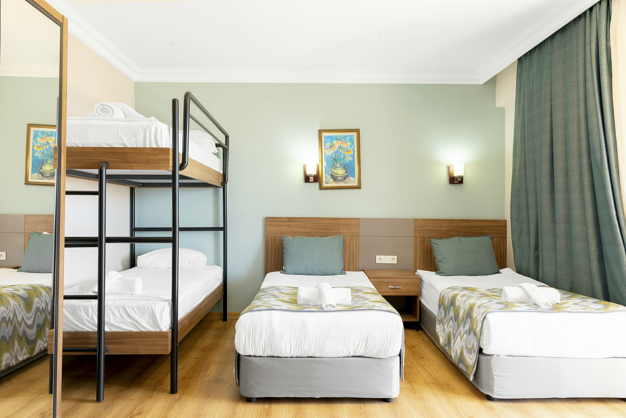 Hotellihuone, jossa kerrossänky ja kaksi erillistä vuodetta. (Tekoälyn luoma teksti)