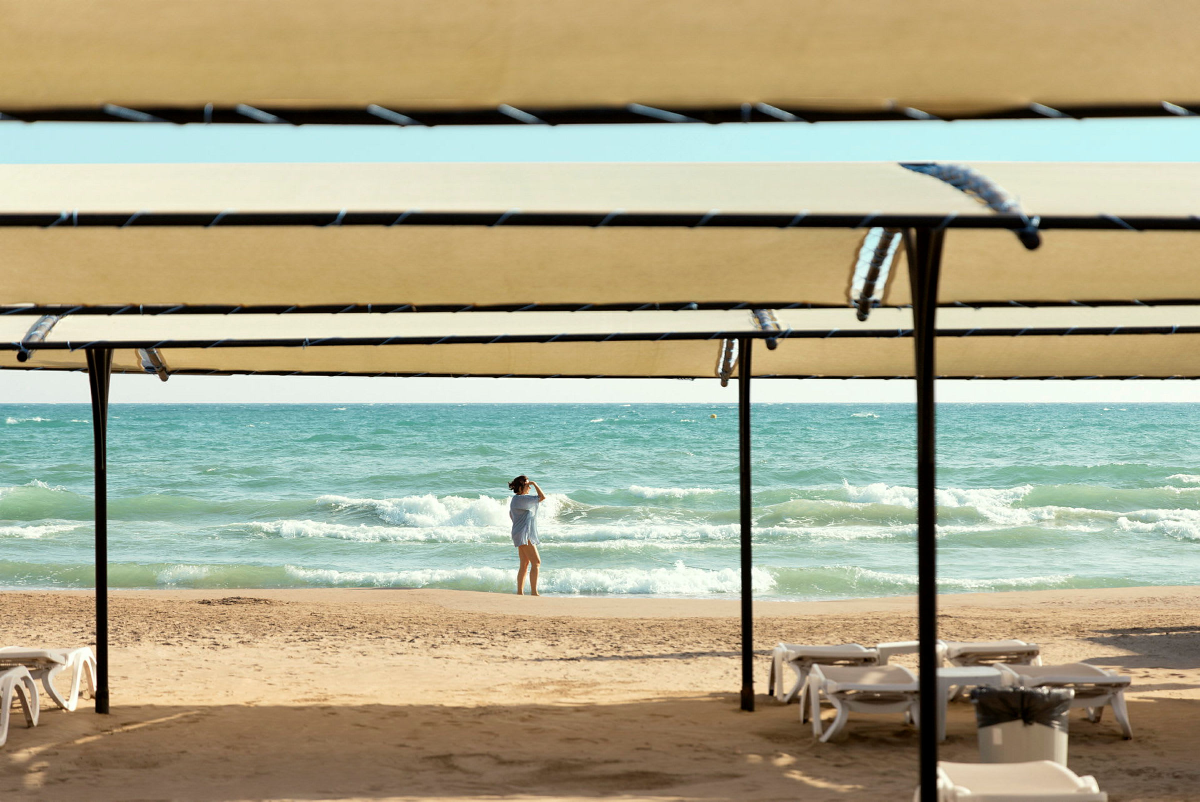 Henkilö seisoo rannalla meren edessä, kuvattuna aurinkosuojan läpi. (Tekoälyn luoma teksti)
