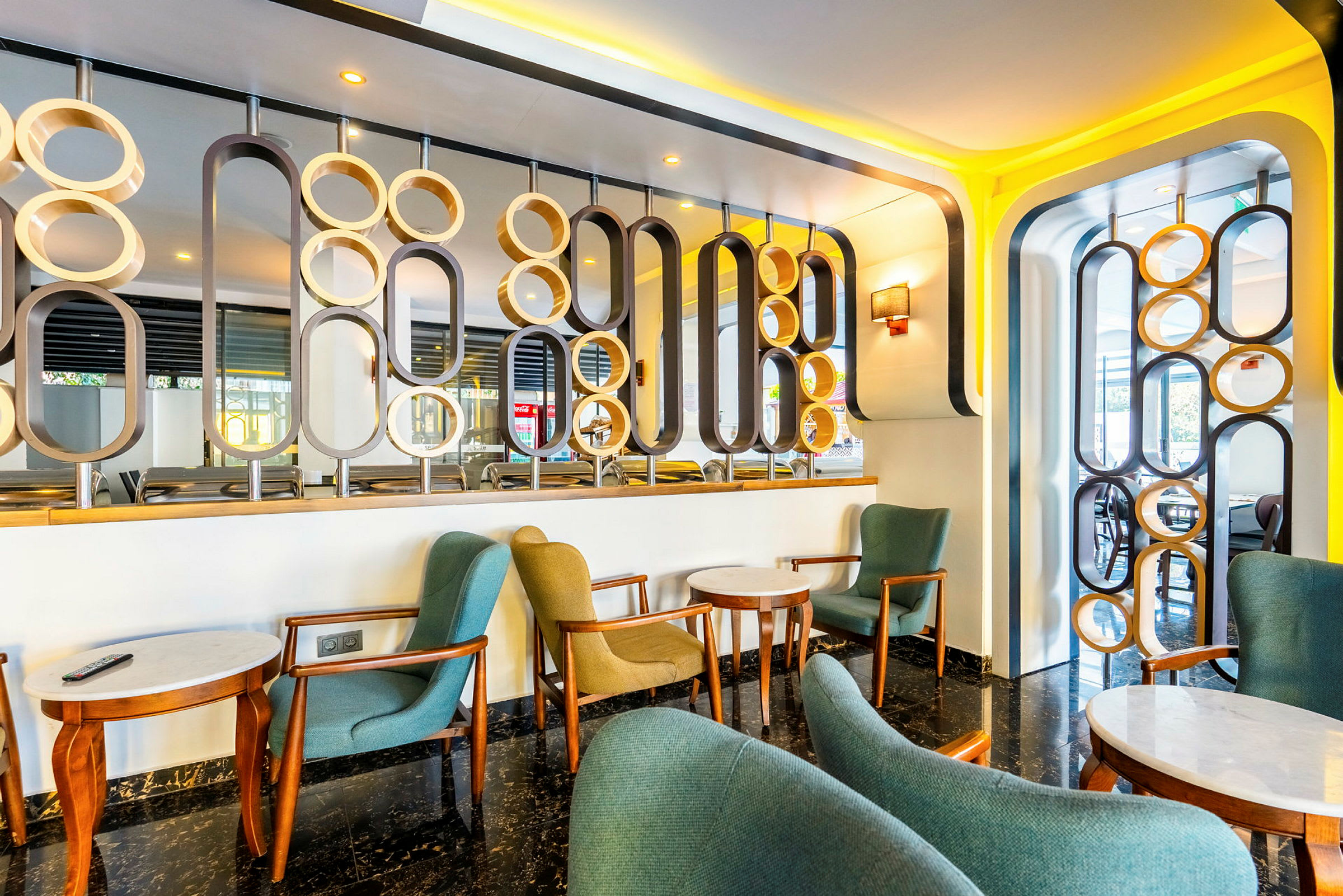 Moderni lounge, jossa on tuoleja, pöytiä ja koristeellisia suunnitteluelementtejä. (Tekoälyn luoma teksti)