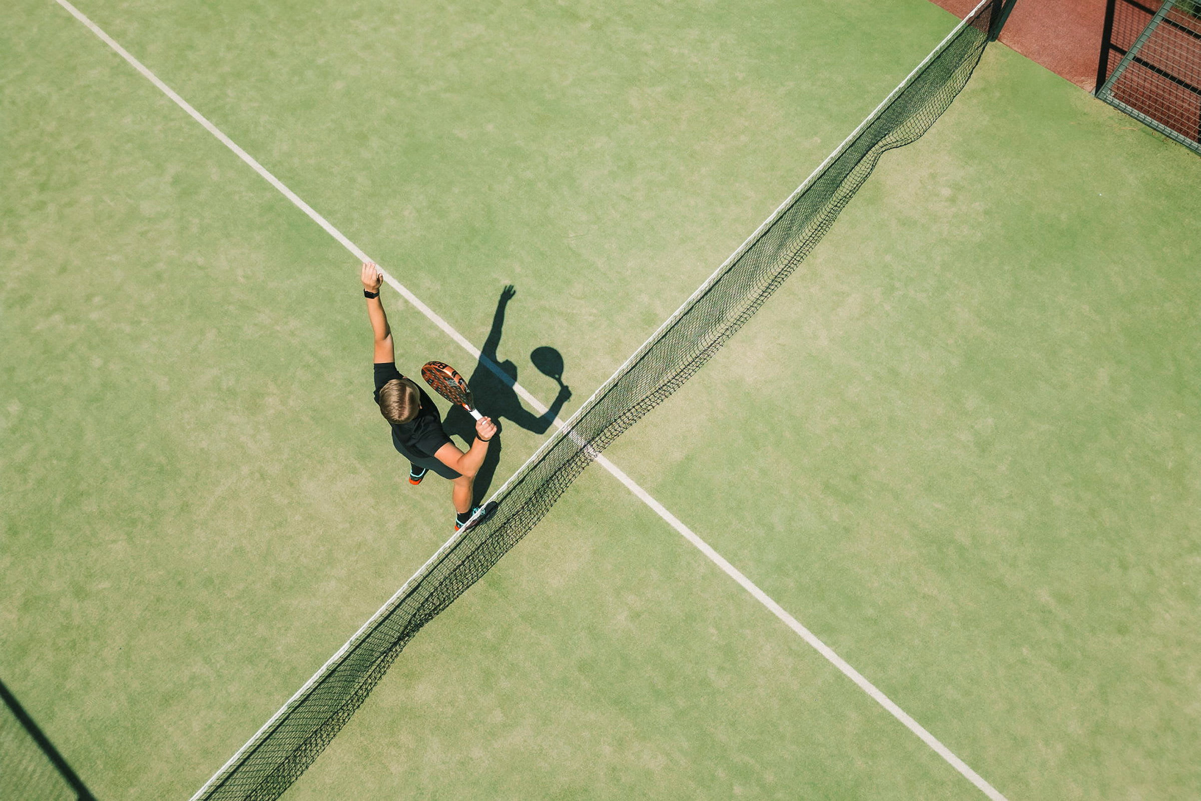 Henkilö pelaa tennistä vihreällä kentällä ja on lyömässä palloa mailalla. (Tekoälyn luoma teksti)