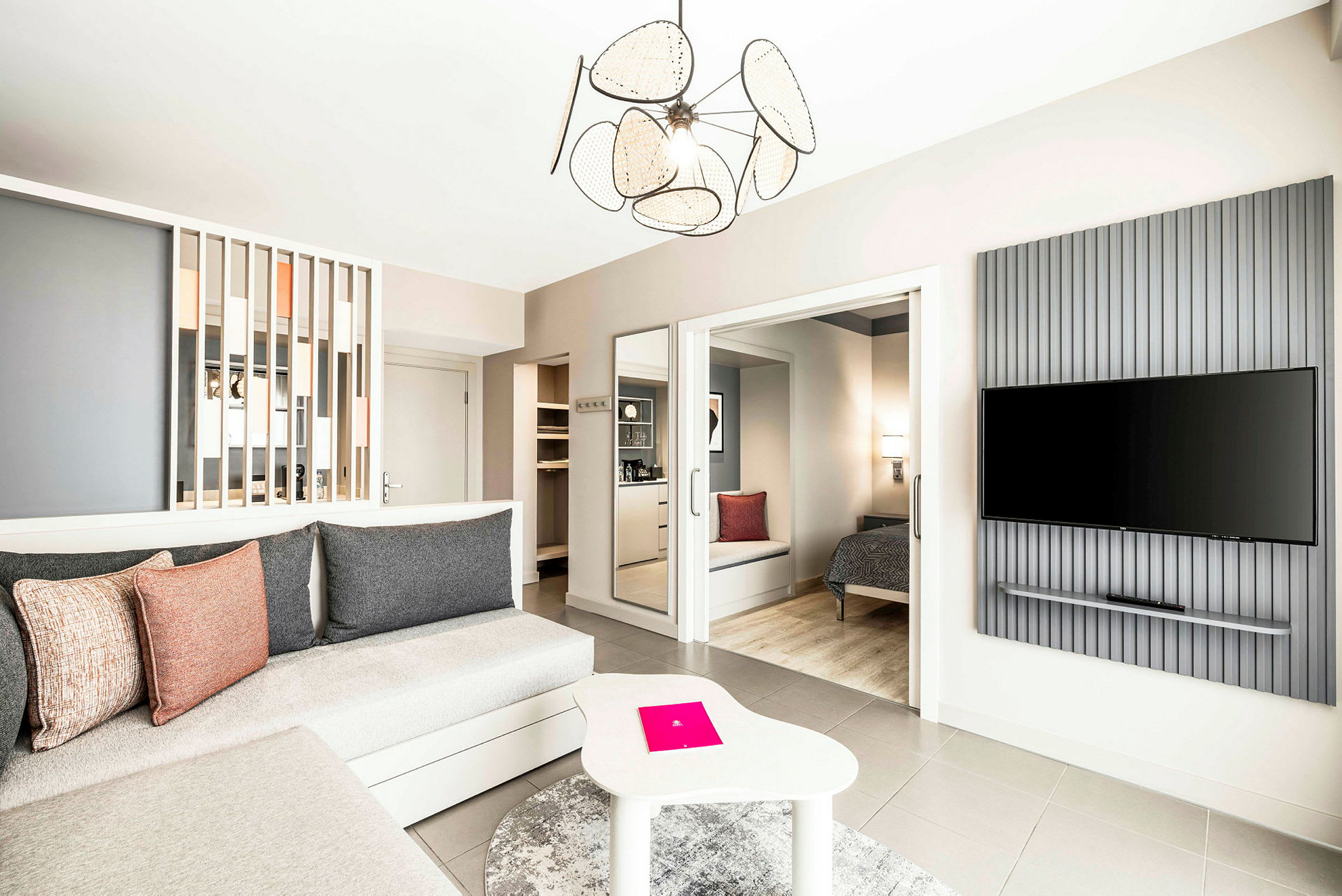 Tilava ja modernisti sisustettu hotellihuone, jossa istuinryhmä, makuutila ja seinälle kiinnitetty TV. (Tekoälyn luoma teksti)
