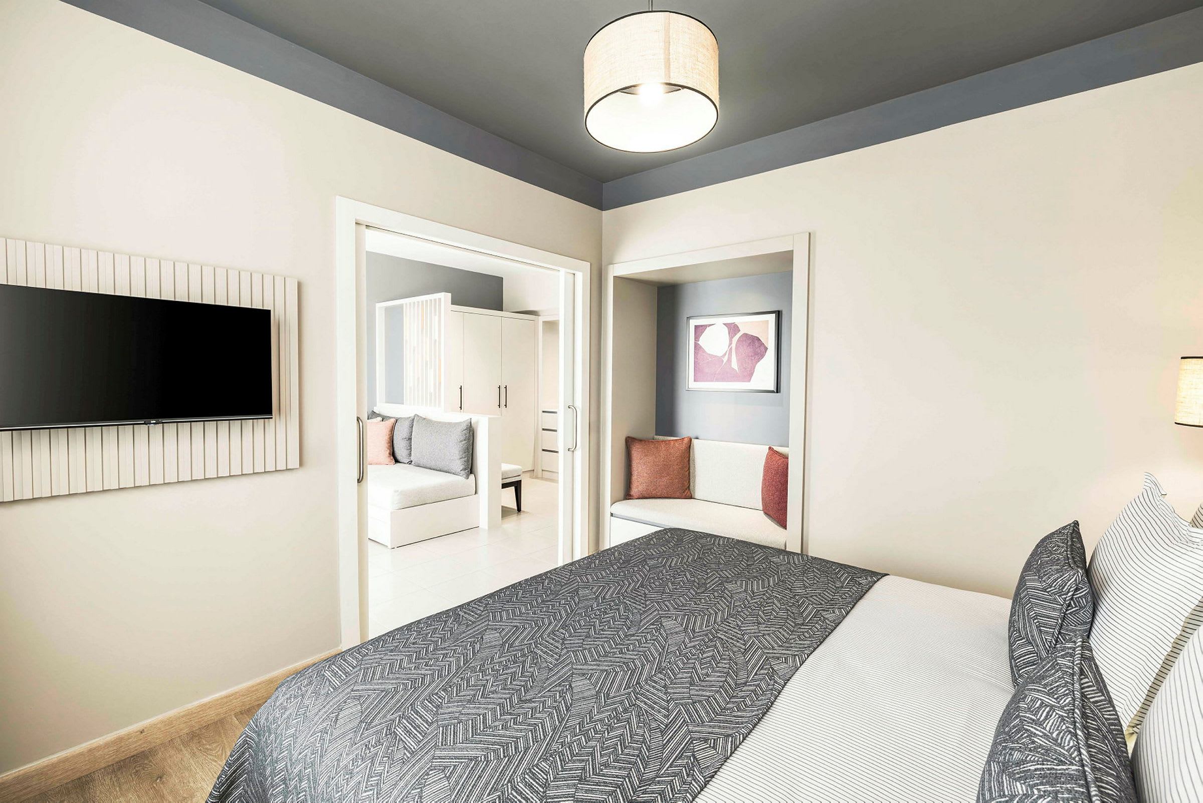 Moderni hotellihuone, jossa sänky, tekstiilit ja istuinalue. (Tekoälyn luoma teksti)