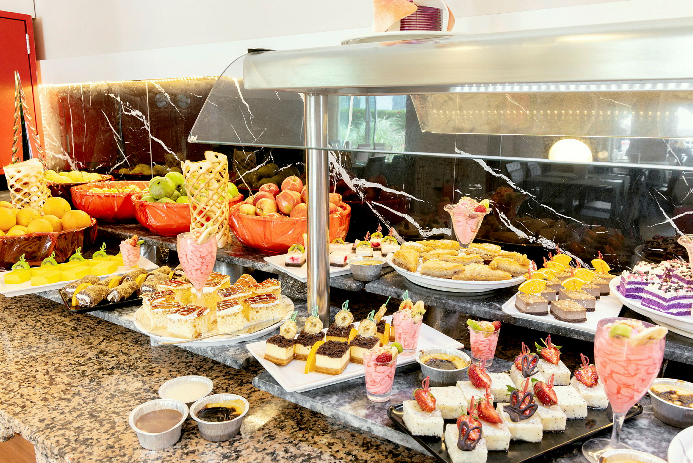 Buffet, jossa erilaisia jälkiruokia ja tuoreita hedelmiä. (Tekoälyn luoma teksti)