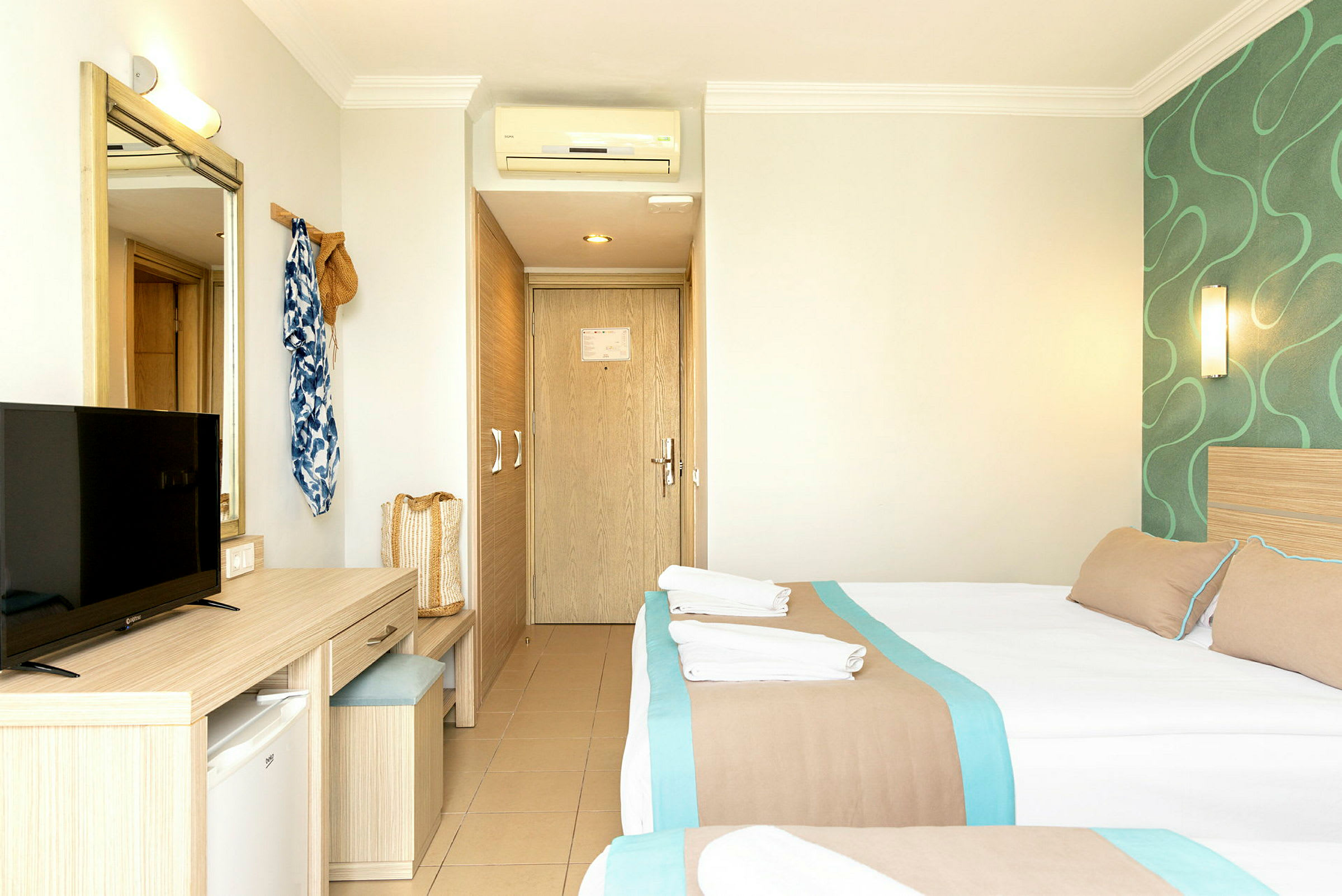 Hotellihuone, jossa kaksi vuodetta, peili, televisio ja kirjoituspöytä. (Tekoälyn luoma teksti)