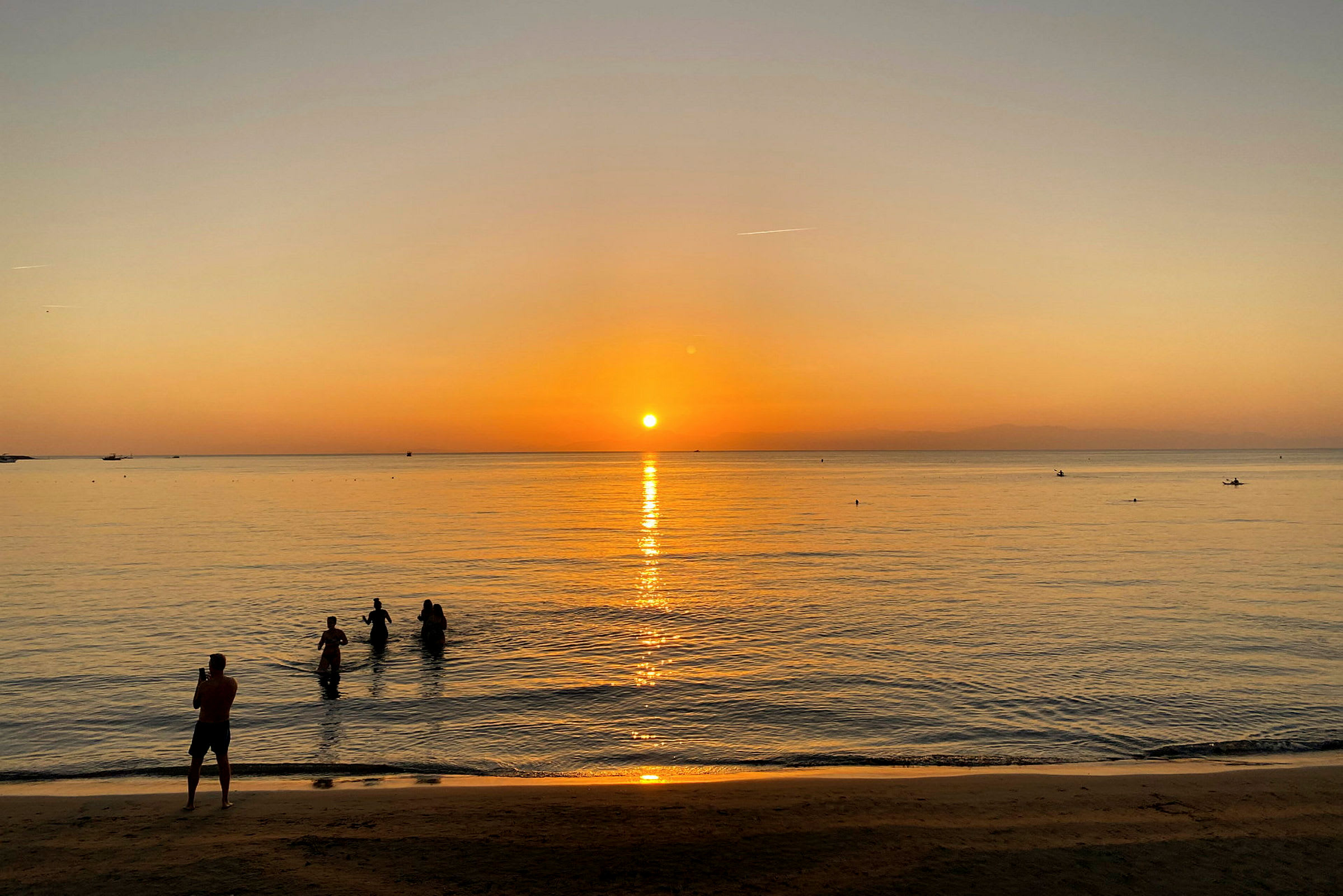 Ranta auringonlaskun aikaan ihmiset vedessä. (Tekoälyn luoma teksti)