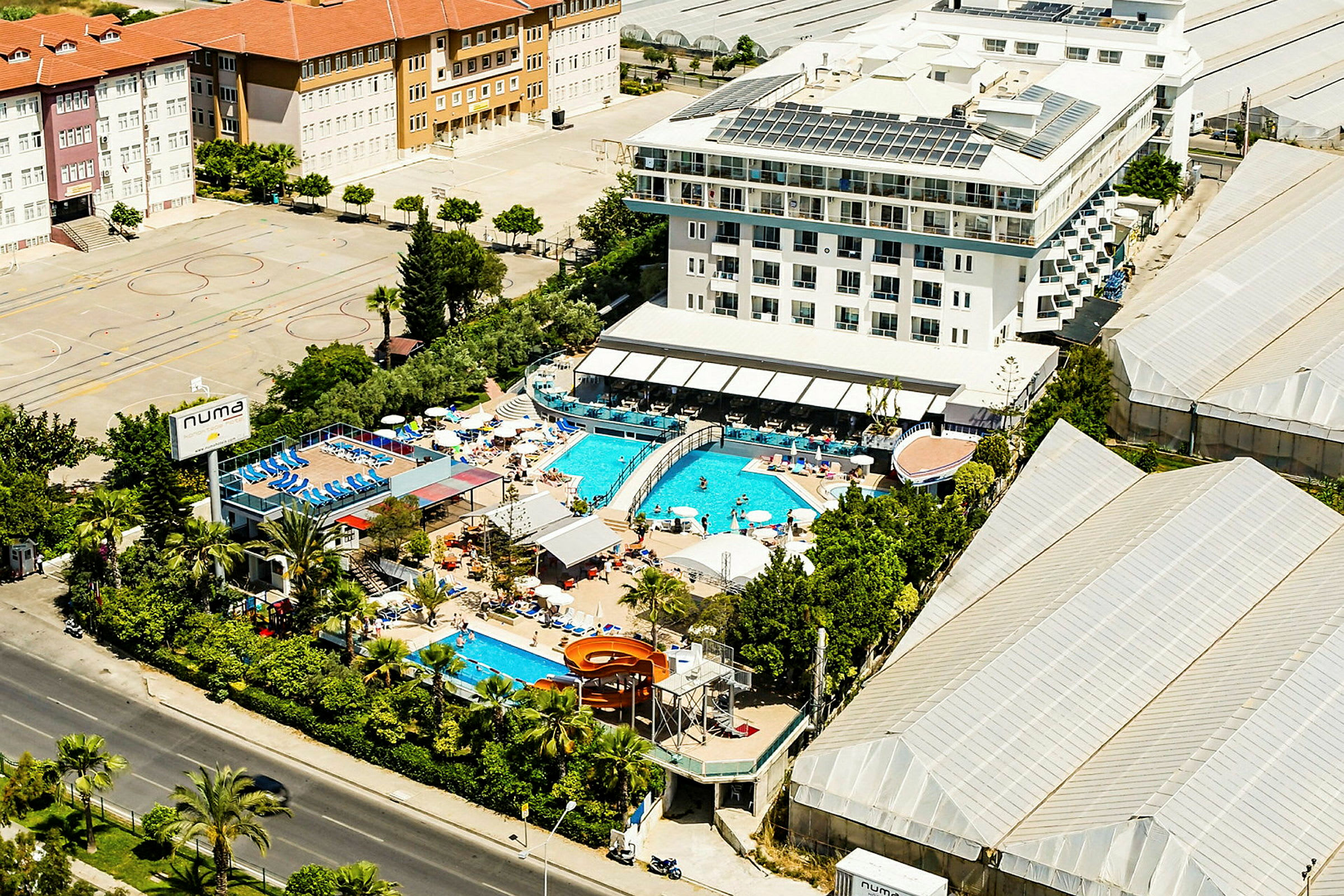 Ilmakuva hotellista, jossa on ulkouima-altaita ja ympäröiviä rakennuksia. (Tekoälyn luoma teksti)