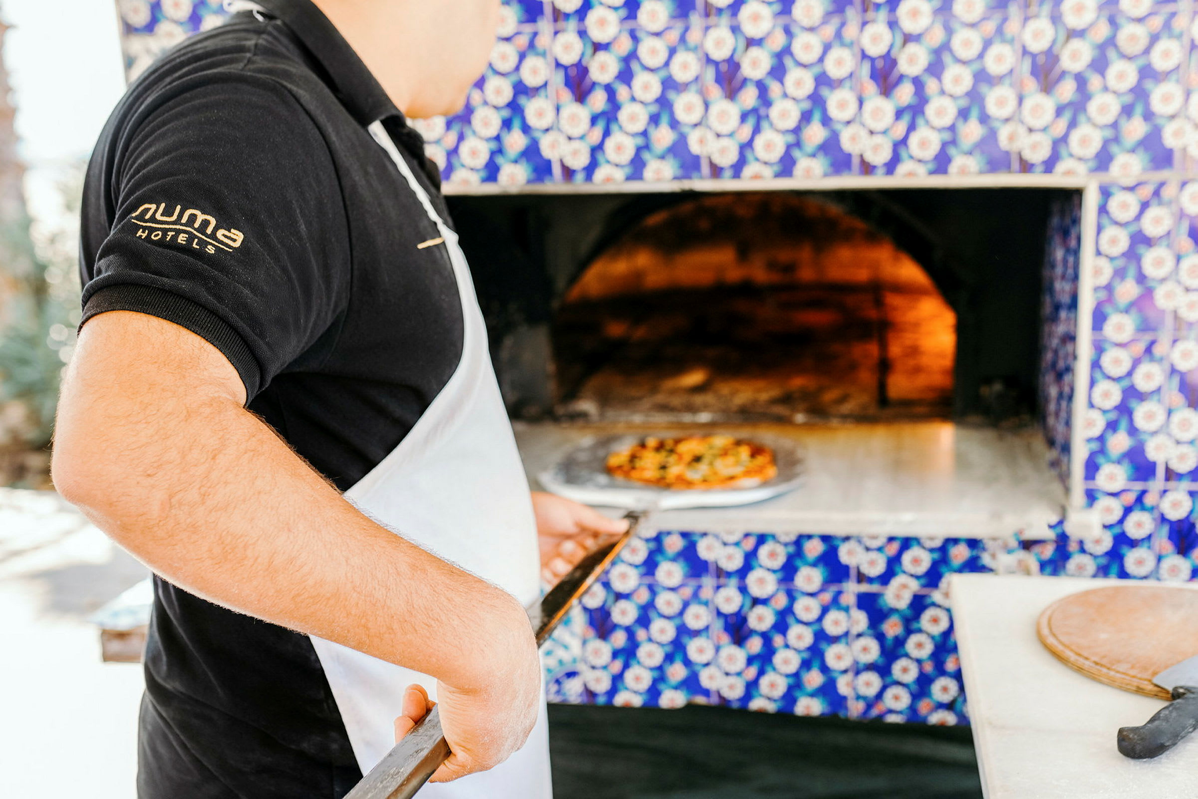 Henkilö pitää pizzalapion puu-uunin edessä. (Tekoälyn luoma teksti)