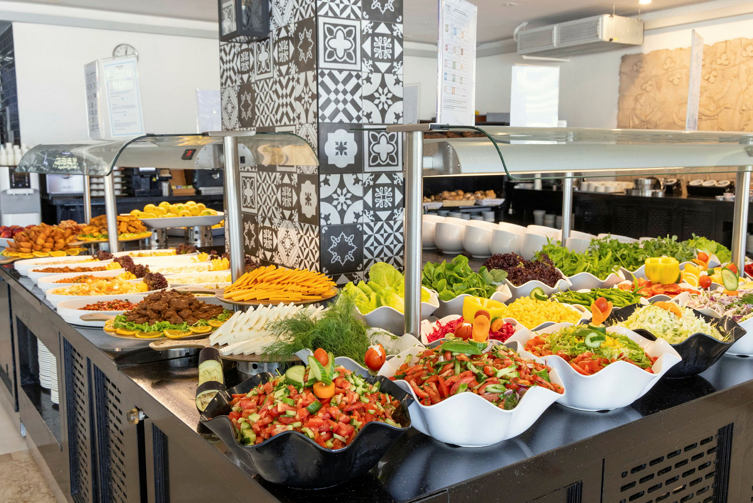 Buffet, jossa on erilaisia ruokia, mukaan lukien salaatteja, vihanneksia ja muita lisukkeita, koristeilla ja tarjoiluilla. (Tekoälyn luoma teksti)