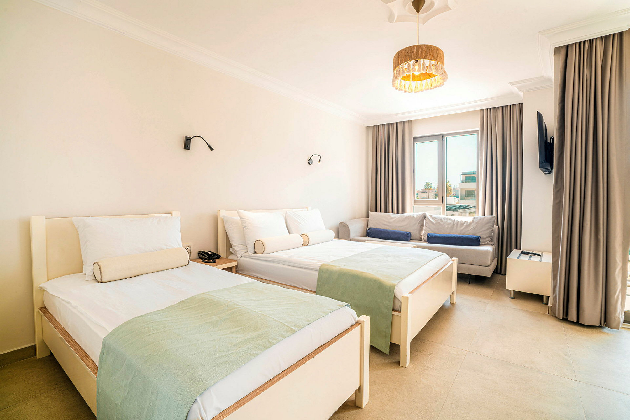 Hotellihuone, jossa kaksi yhden hengen sänkyä, sohva ja ikkuna. (Tekoälyn luoma teksti)