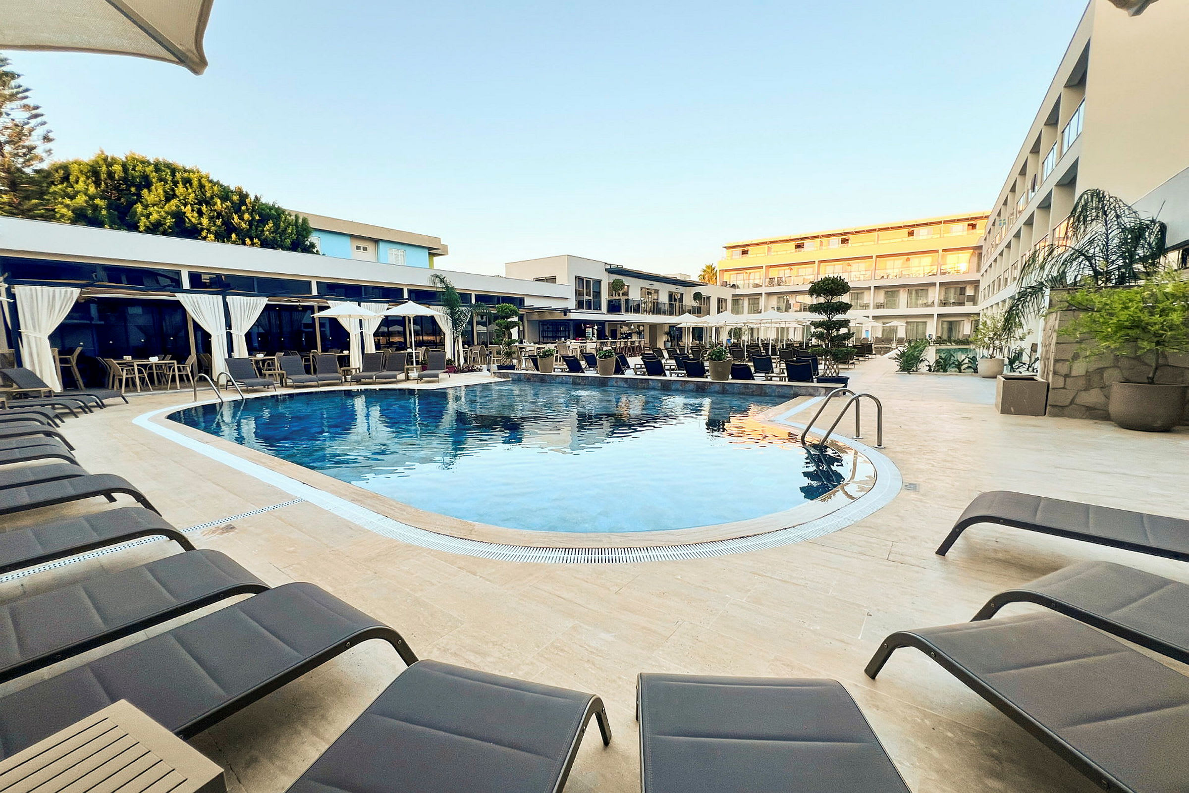 Ulkouima-allas, aurinkotuoleja ja hotellirakennuksia taustalla. (Tekoälyn luoma teksti)