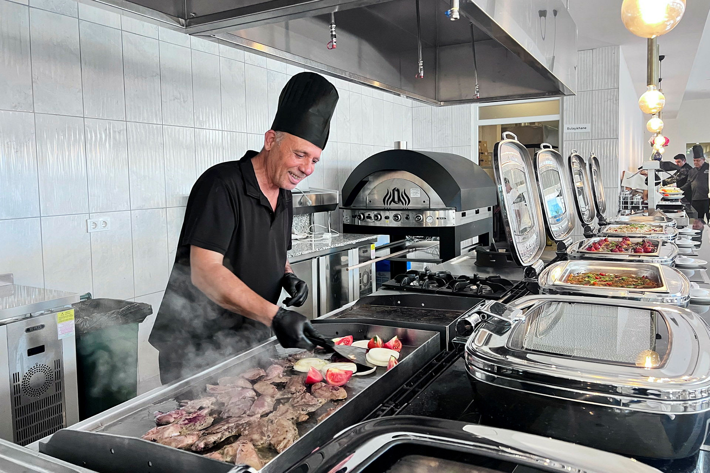 Kokki valmistaa ruokaa grillissä buffet-ympäristössä. (Tekoälyn luoma teksti)