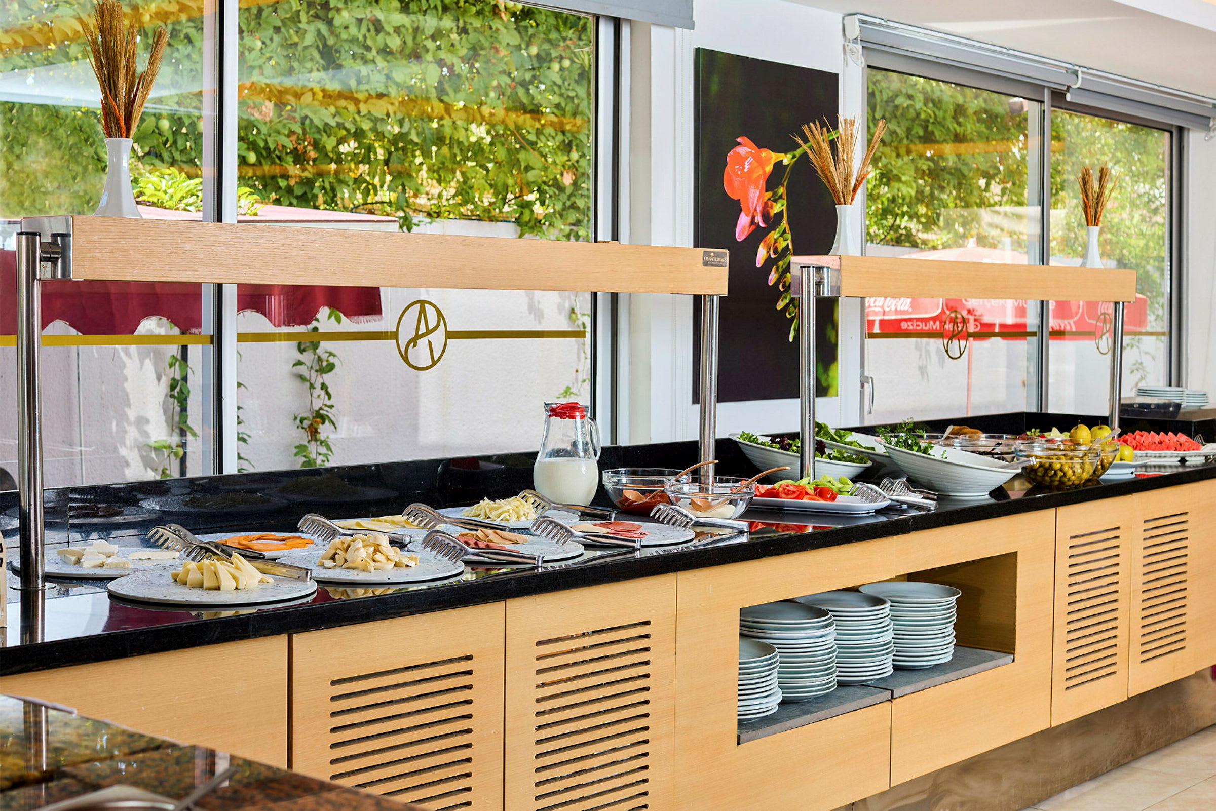 Buffet, jossa erilaisia ruokalajeja ja lisukkeita sekä astioita ravintolassa. (Tekoälyn luoma teksti)