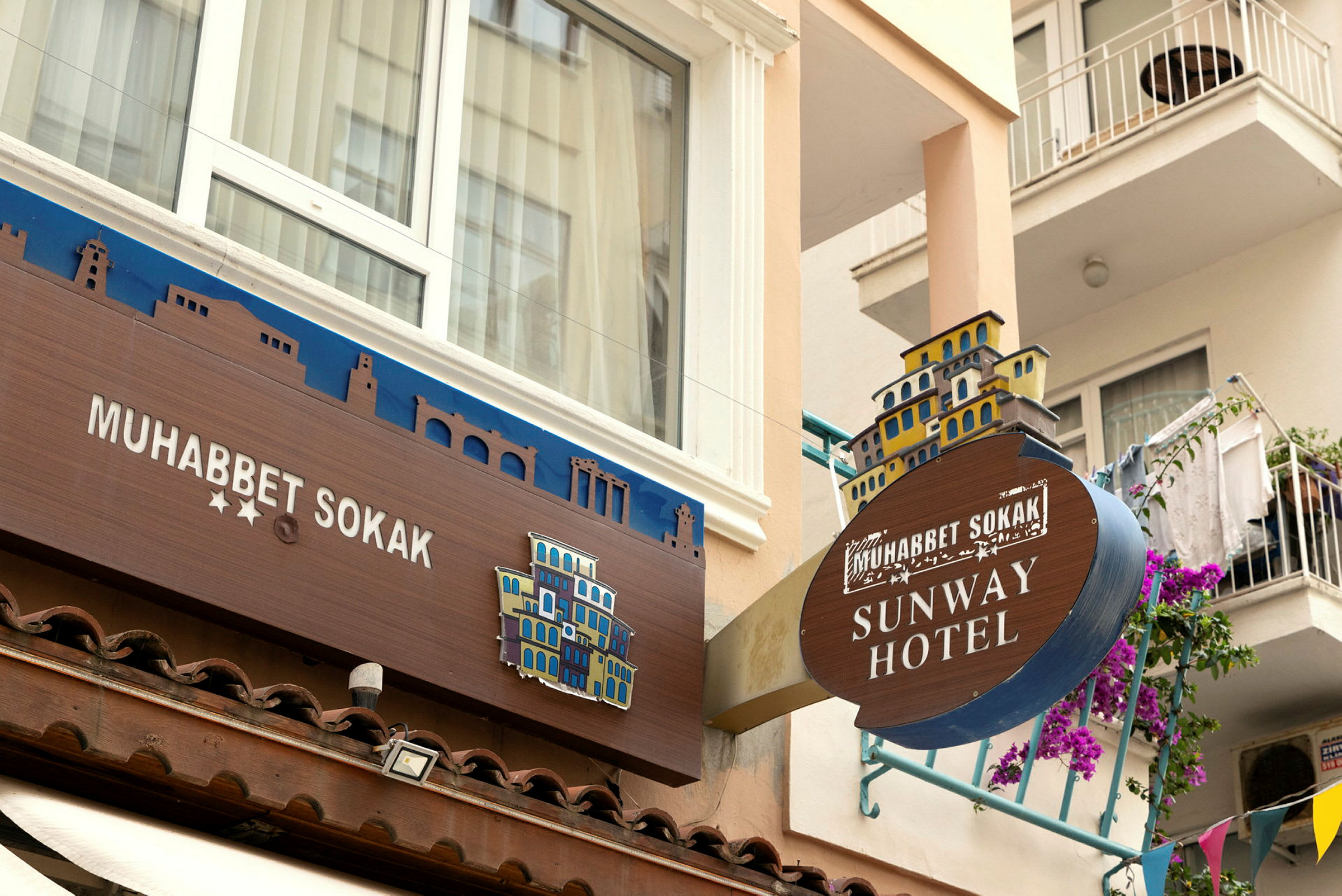 Kuva hotellin julkisivusta, jossa näkyvät kyltit 'Muhabbet Sokak' ja 'Sunway Hotel'. (Tekoälyn luoma teksti)