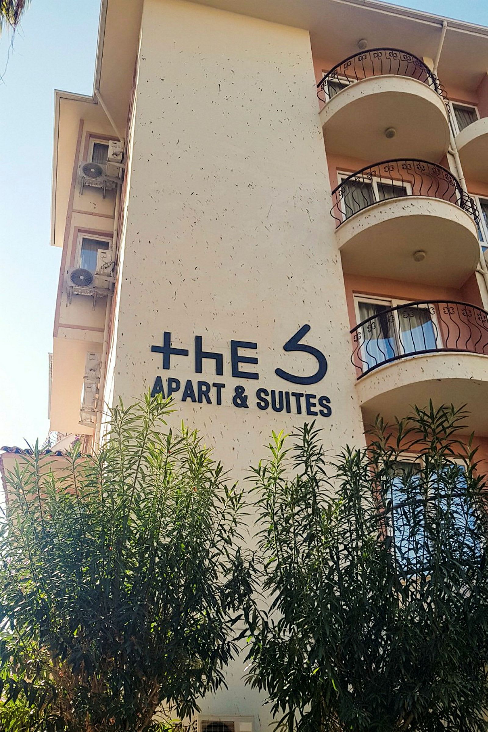 Rakennus, jossa kyltti "The S Apart & Suites", ympärillä puita. (Tekoälyn luoma teksti)