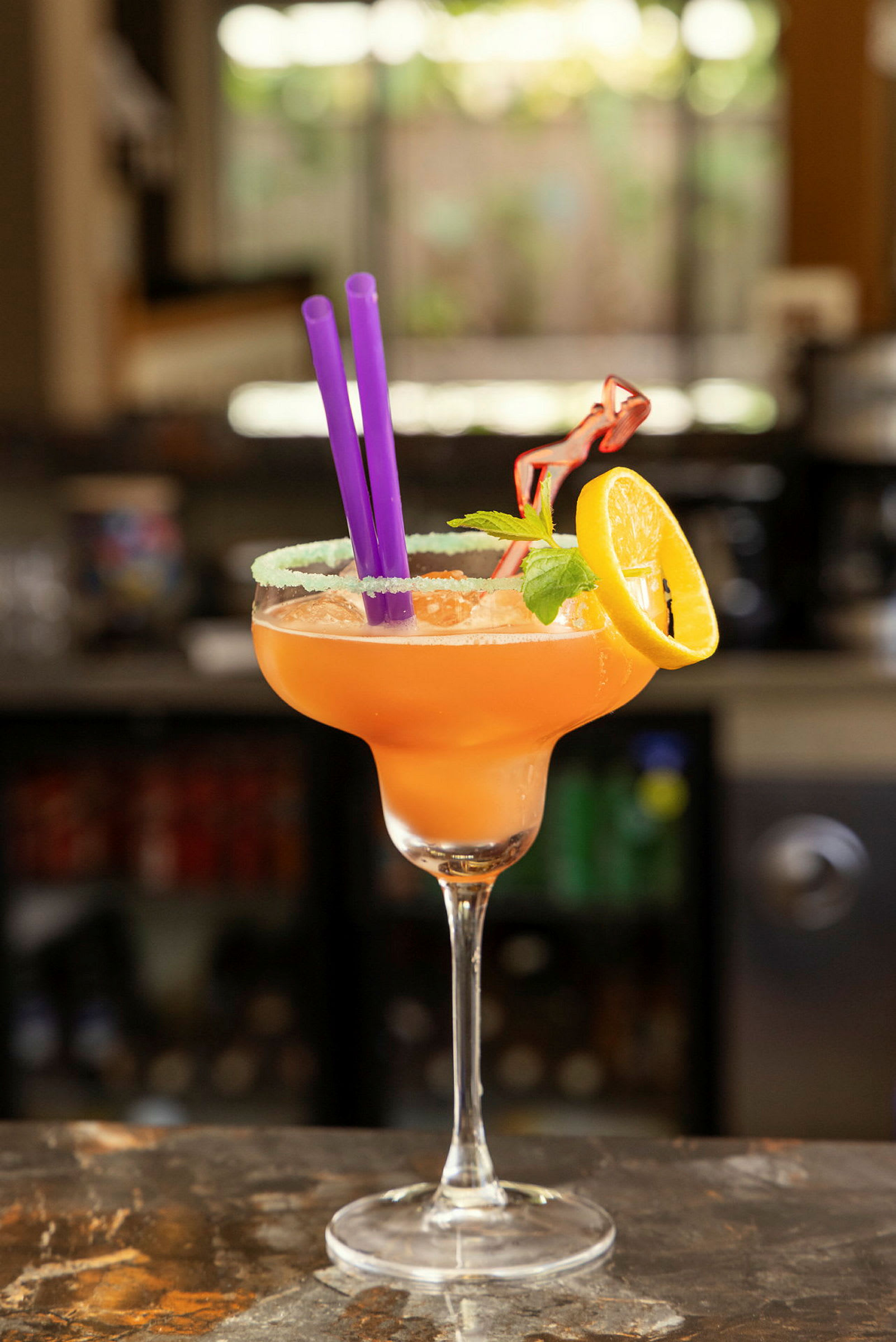 Cocktail tarjoiltuna lasissa, jossa on sitruunaviipale, mintunlehtiä ja pillejä. (Tekoälyn luoma teksti)