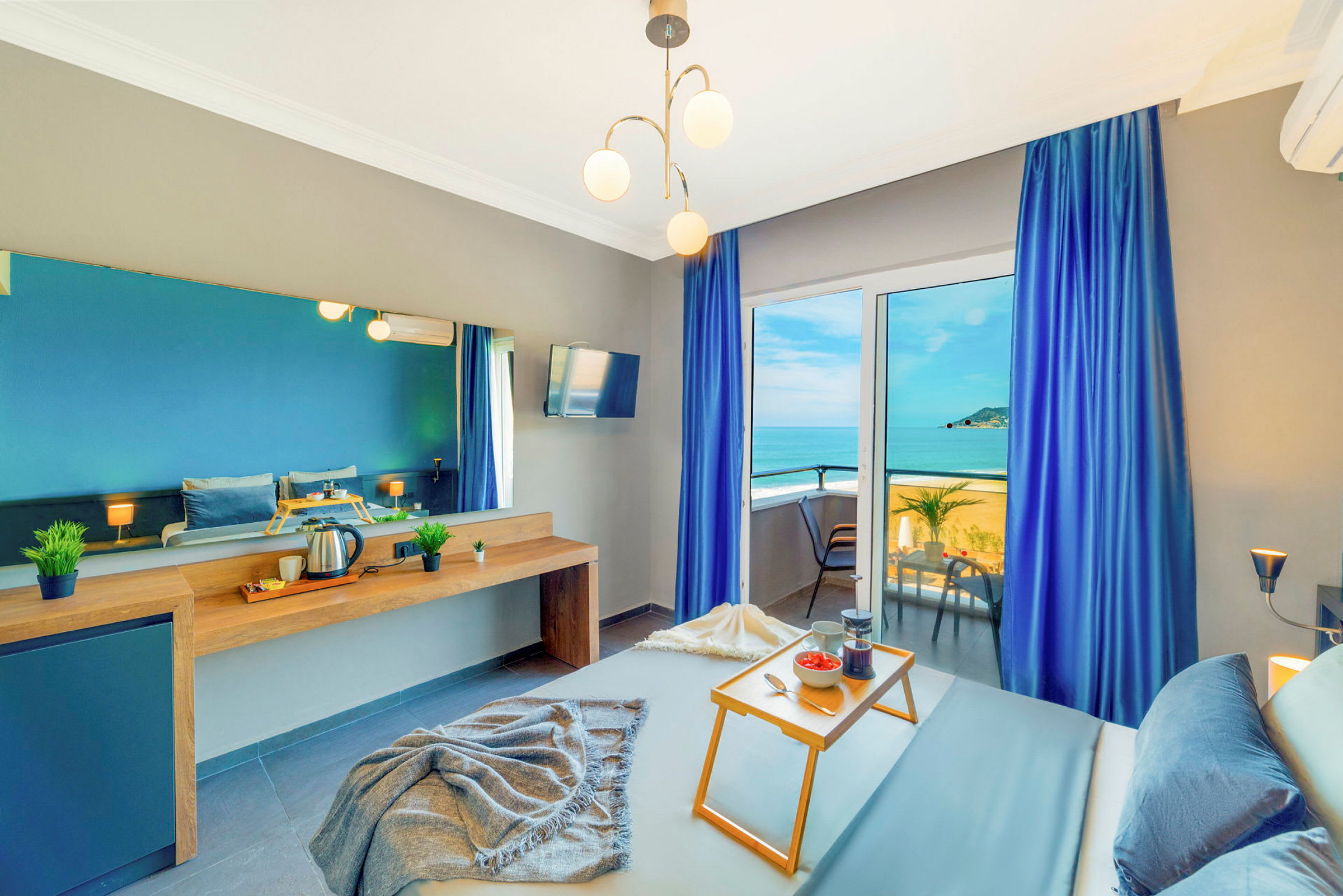 Hotellihuone merinäköalalla, siniset verhot ja aamiaistarjotin sängyllä. (Tekoälyn luoma teksti)
