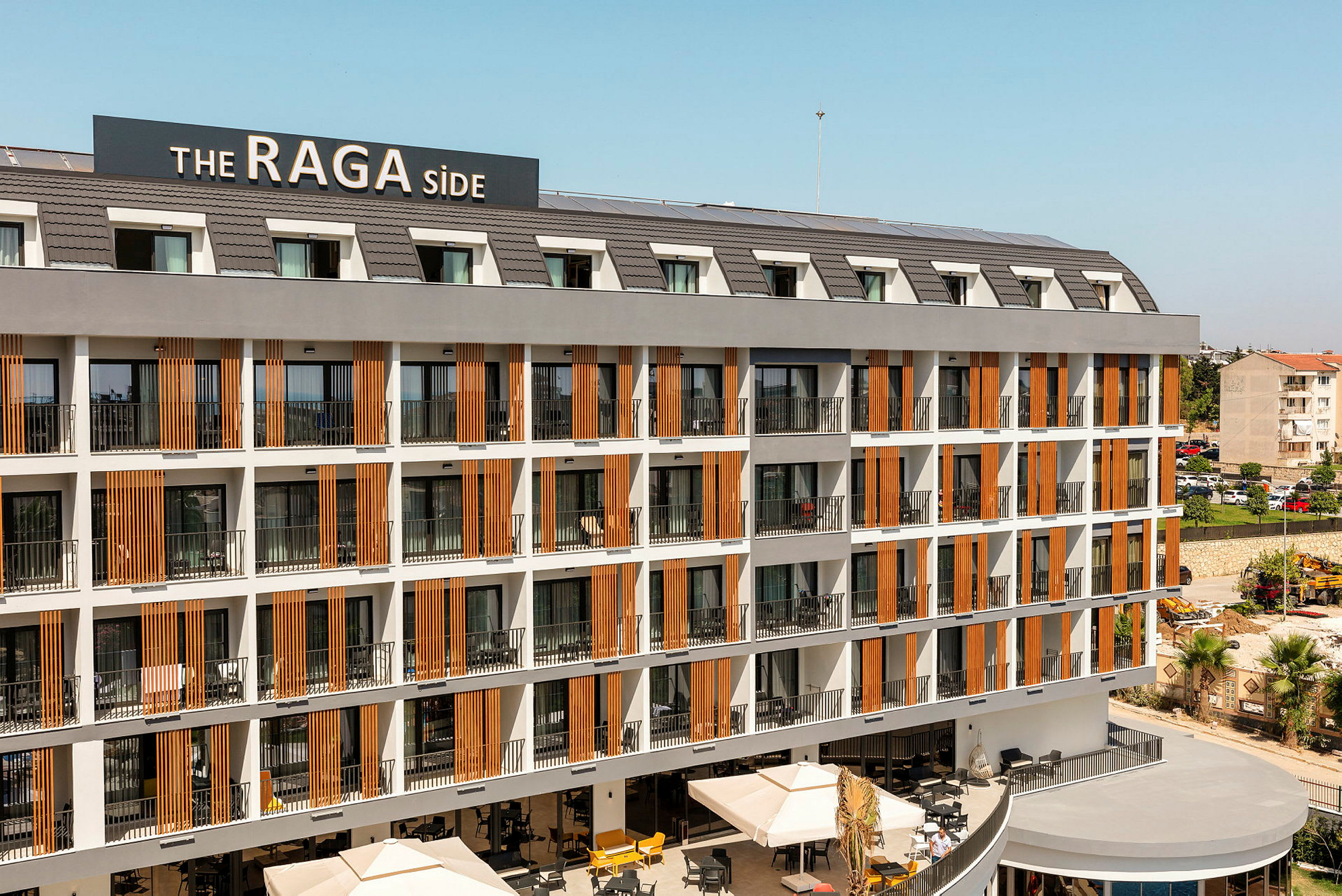 Hotellikompleksi, jossa on useita kerroksia parvekkeita ja kyltti, jossa lukee 'The RAGA Side'. (Tekoälyn luoma teksti)