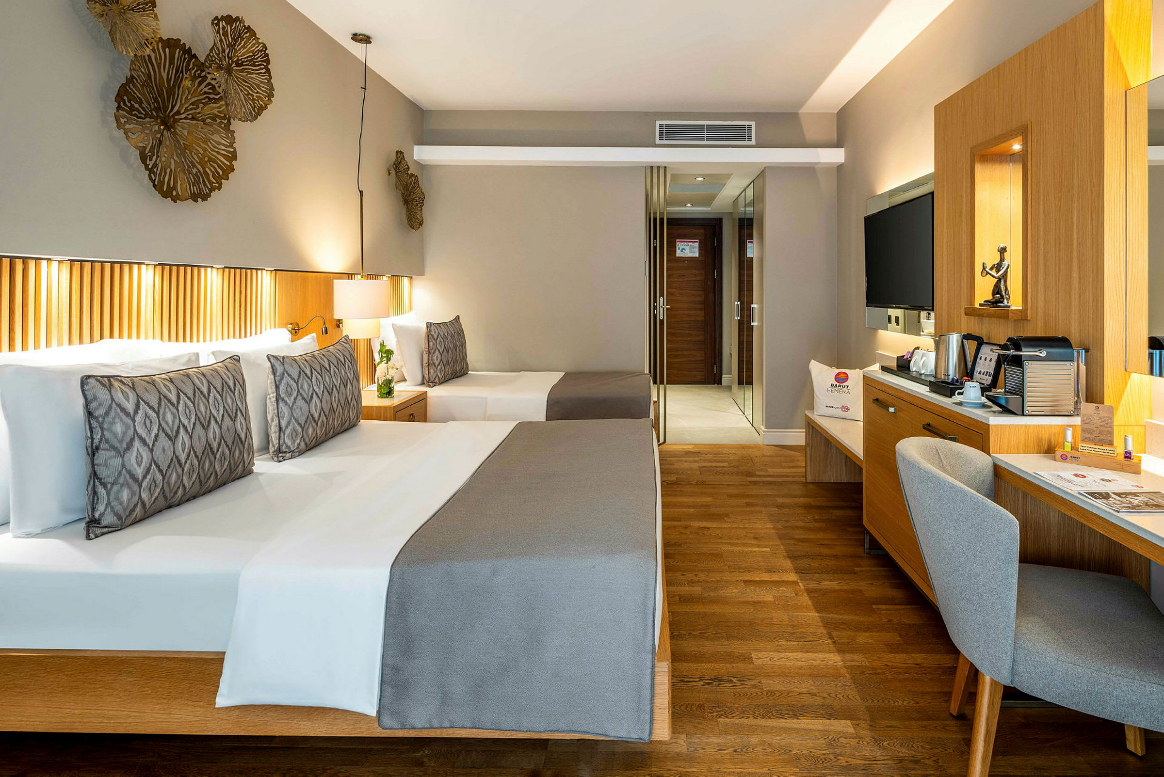 Hotellihuone, jossa kaksi sänkyä, kirjoituspöytä, tuoli ja peili. (Tekoälyn luoma teksti)