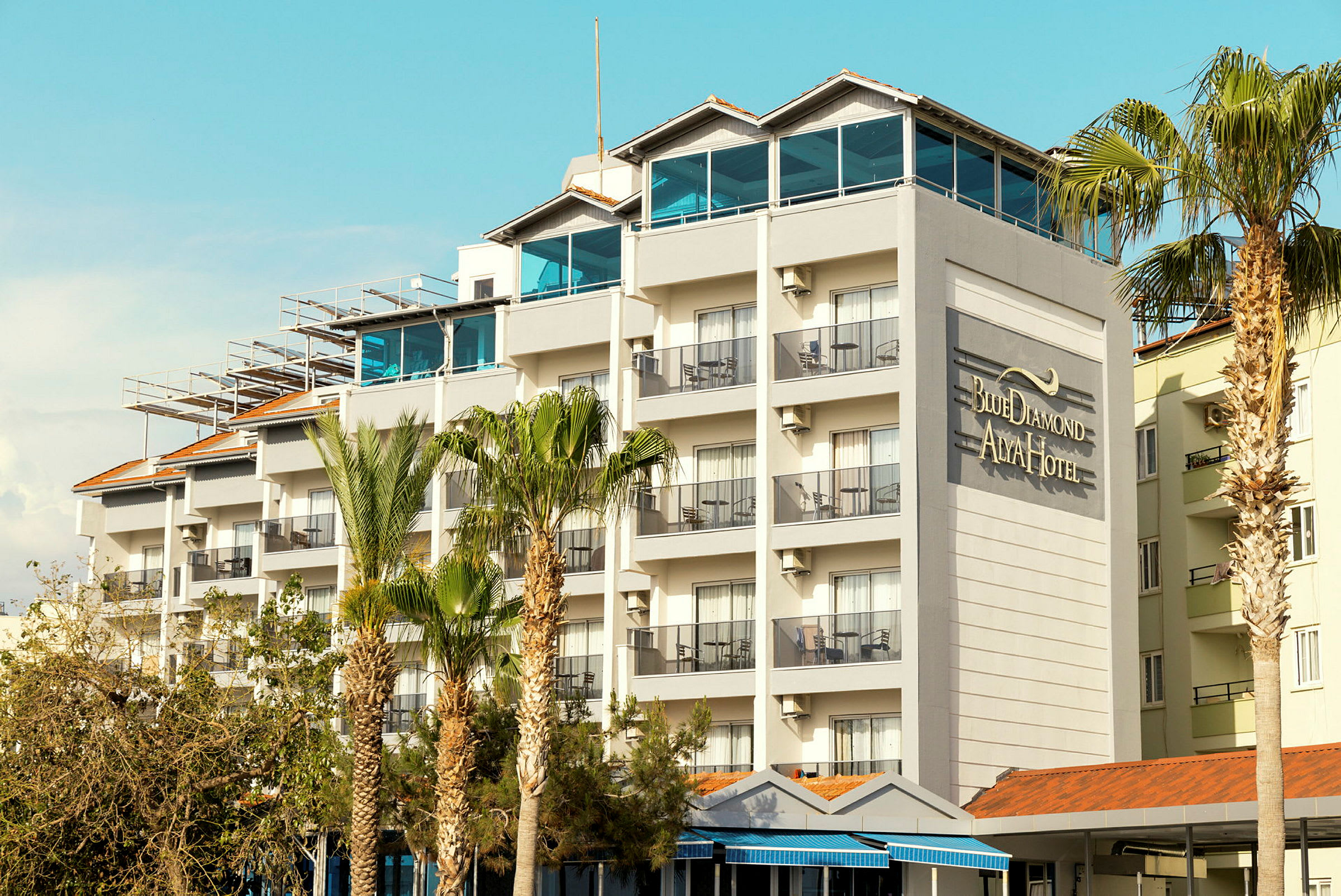 Hotellirakennus, jossa on useita kerroksia ja parvekkeita, sekä seinällä teksti "Blue Diamond Alya Hotel". (Tekoälyn luoma teksti)