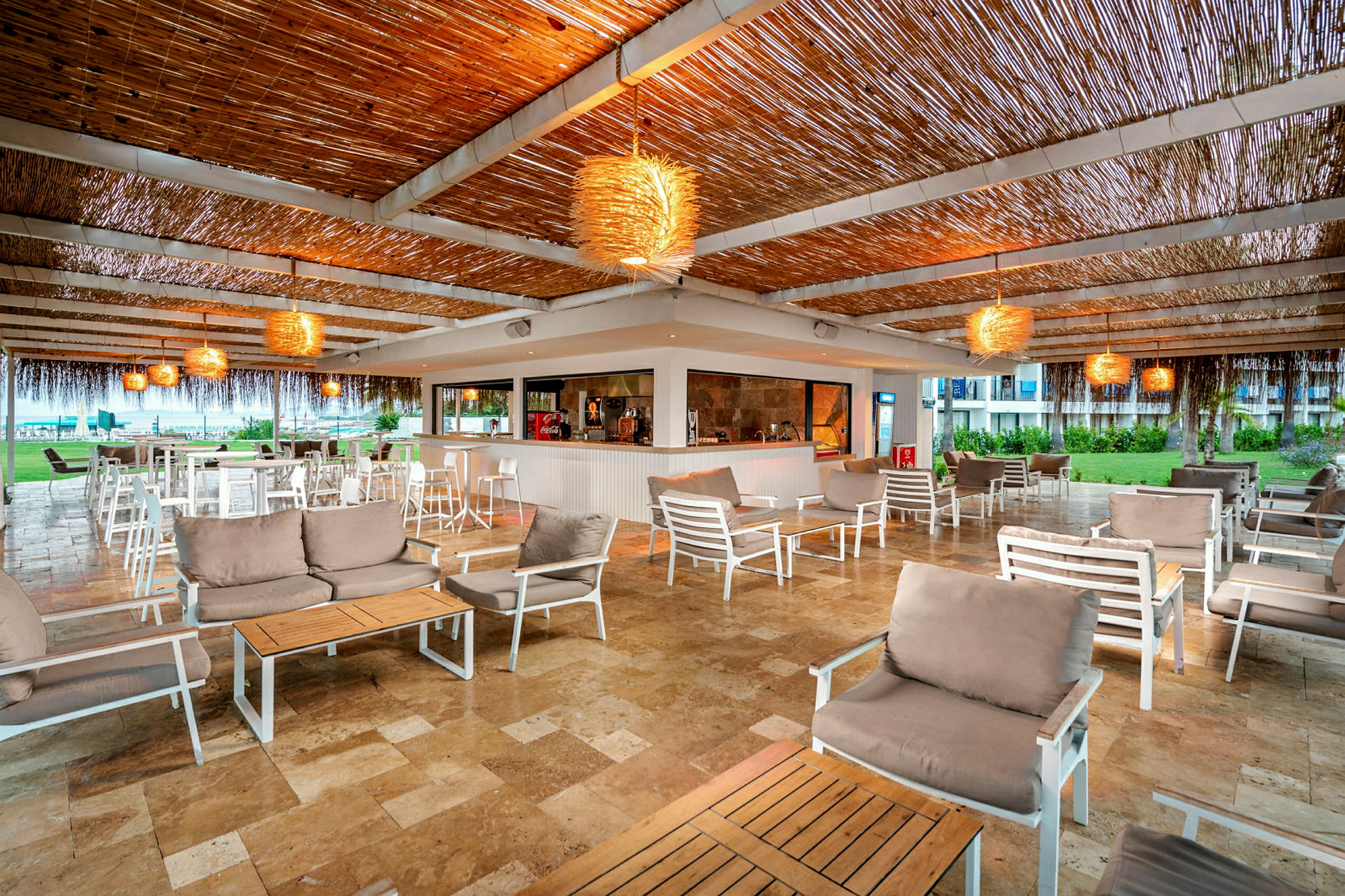 Ulkotila lounge-alueella, pöydät, tuolit ja sohvaryhmät, katto koristeltu puuelementeillä. (Tekoälyn luoma teksti)