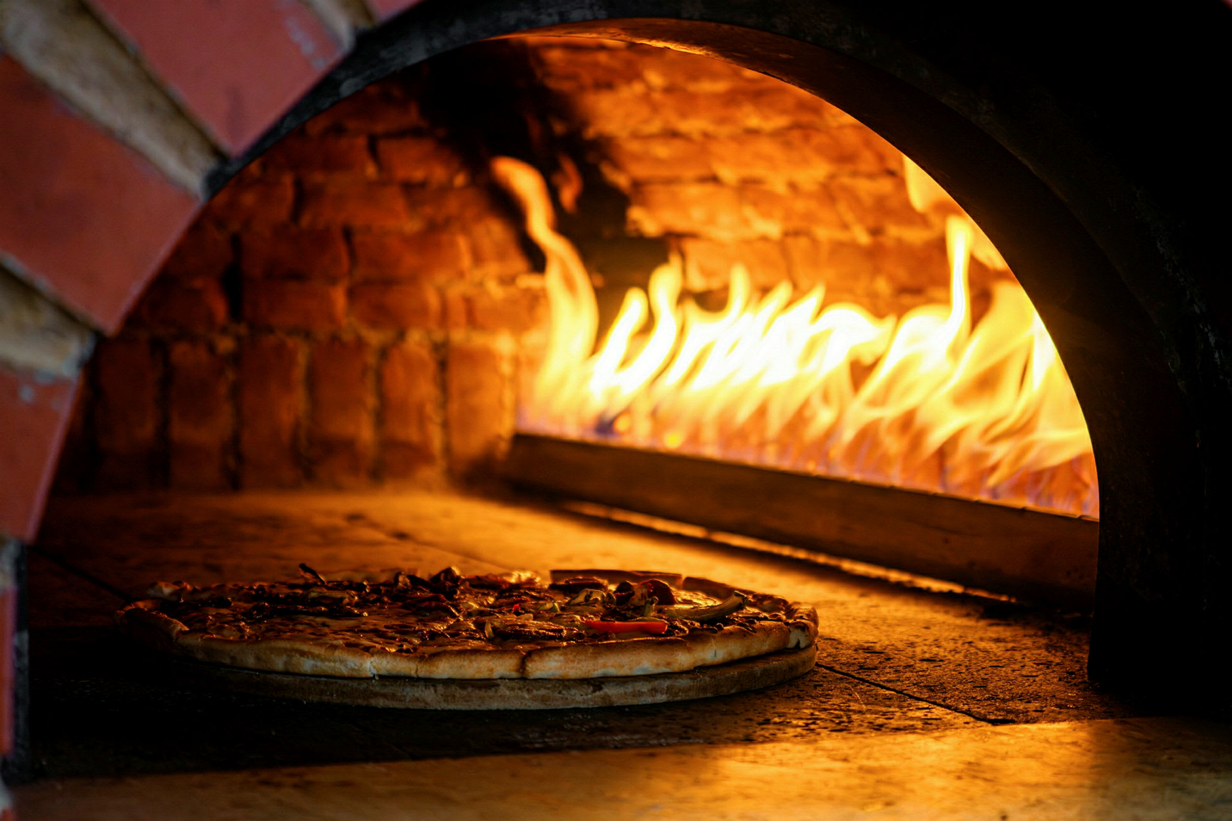 Puulämmitteinen uuni, jossa pizza paistuu. (Tekoälyn luoma teksti)