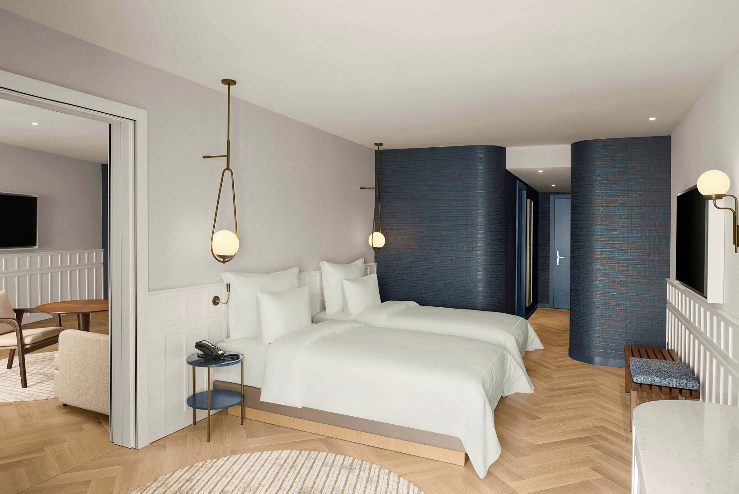 Hotellihuone, jossa on kaksi erillistä vuodetta, vaaleat seinät ja lattiat sekä istuinryhmä pöydän ja tuolien kanssa. (Tekoälyn luoma teksti)