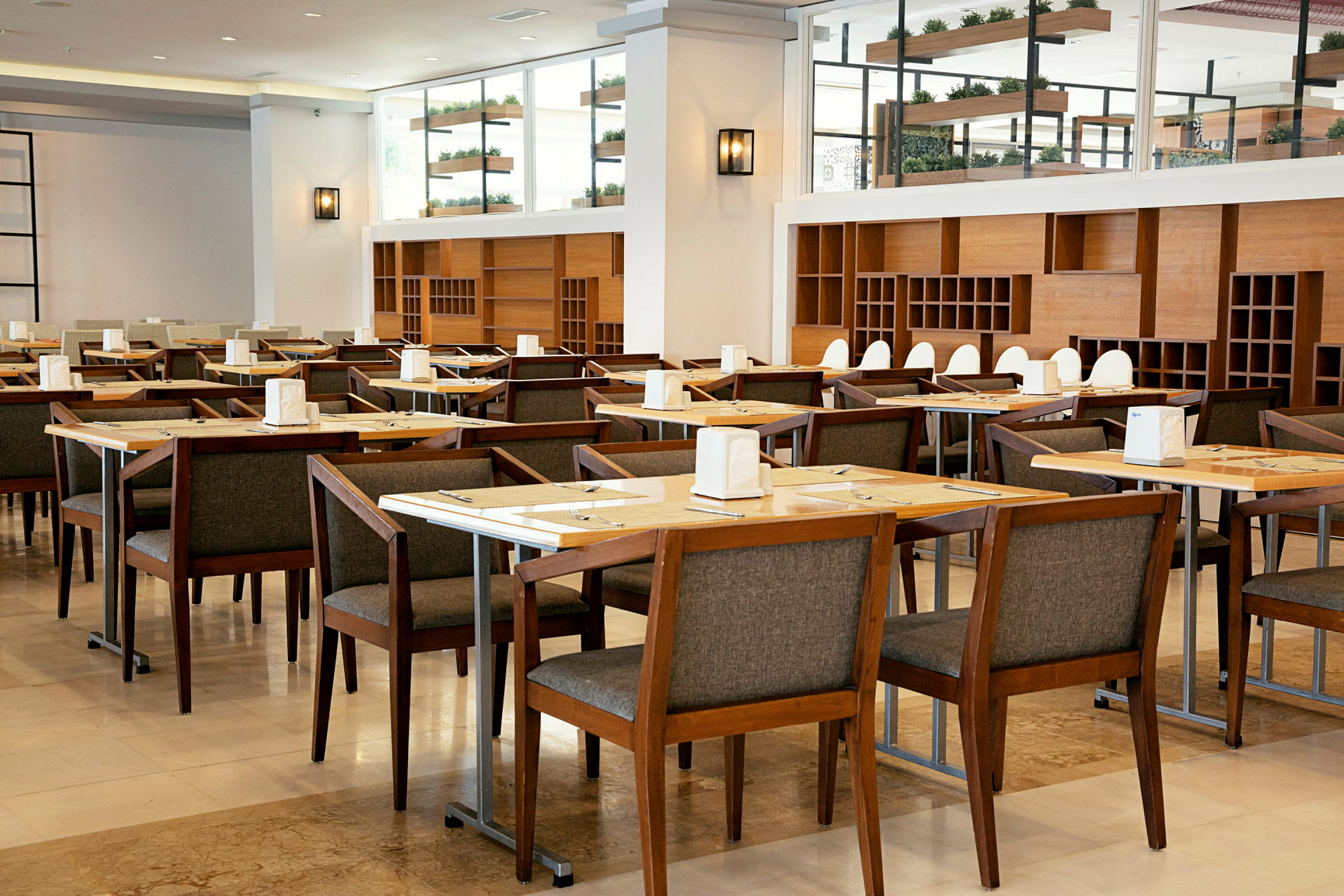 Ravintola, jossa on useita pöytiä ja puisia tuoleja, sisustettu hyllyillä ja koristeilla. (Tekoälyn luoma teksti)