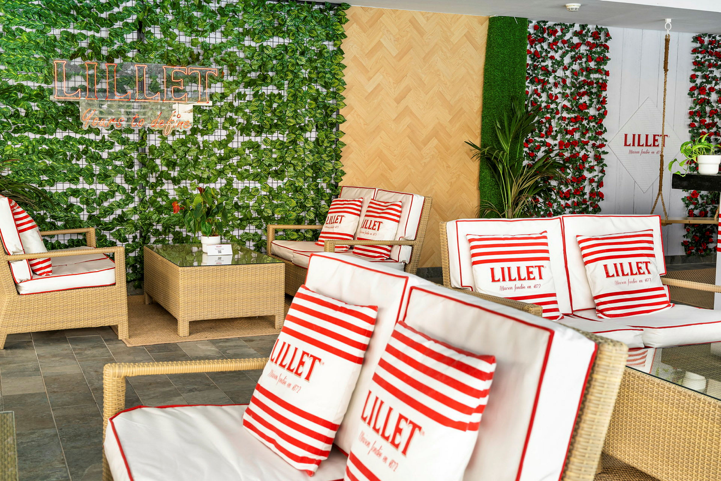 Huone, jossa on rottinkikalusteita ja kasveja, koristeltu tyynyillä, joissa teksti 'Lillet'. (Tekoälyn luoma teksti)