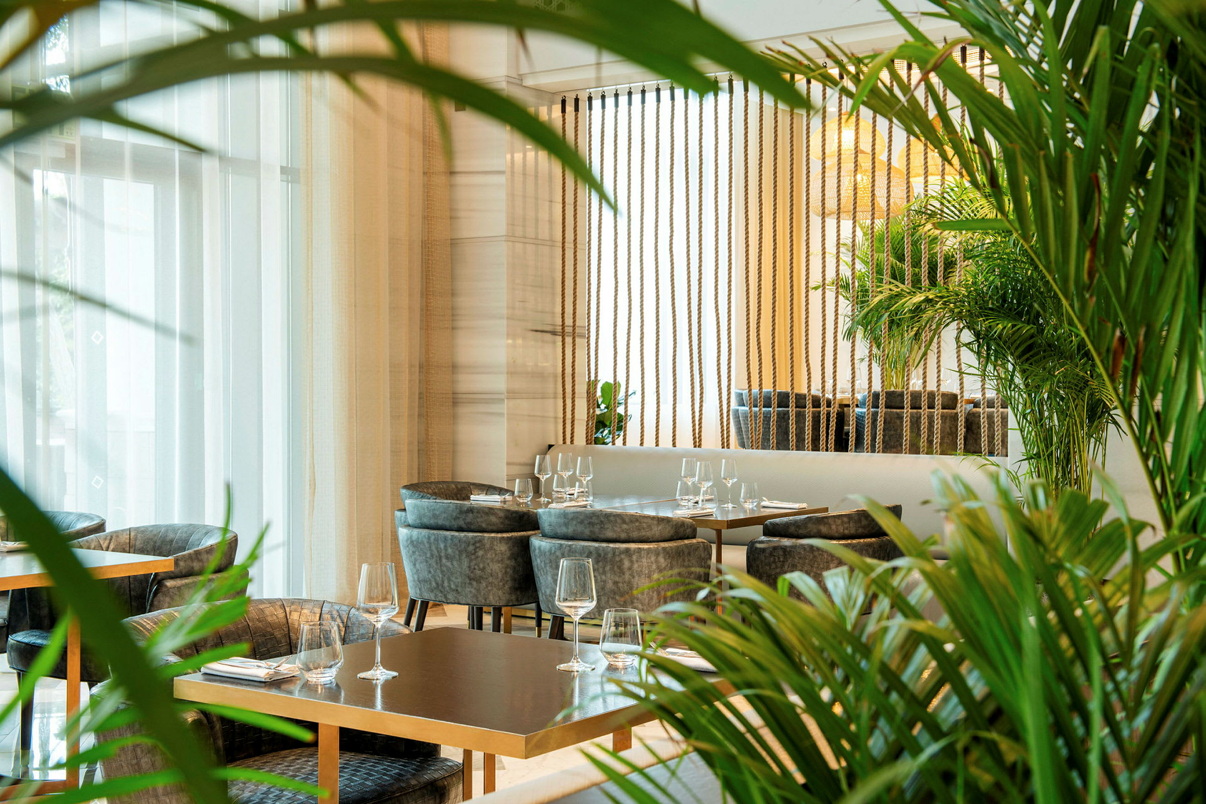 Moderni ravintola, jossa pöytiä ja tuoleja vehreyden ympäröimänä. (Tekoälyn luoma teksti)
