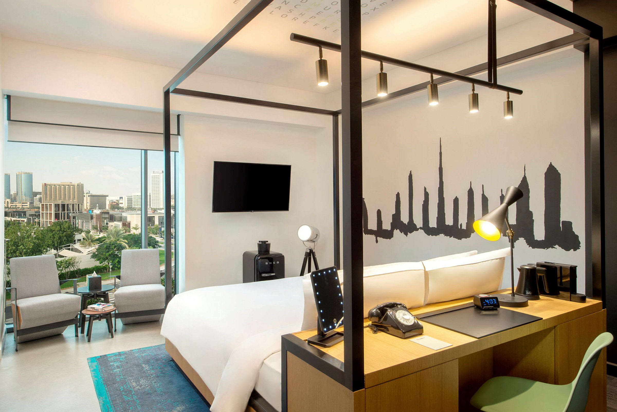 Moderni hotellihuone, jossa on parisänky, kirjoituspöytä ja panoraamanäkymät kaupungin ylle. (Tekoälyn luoma teksti)