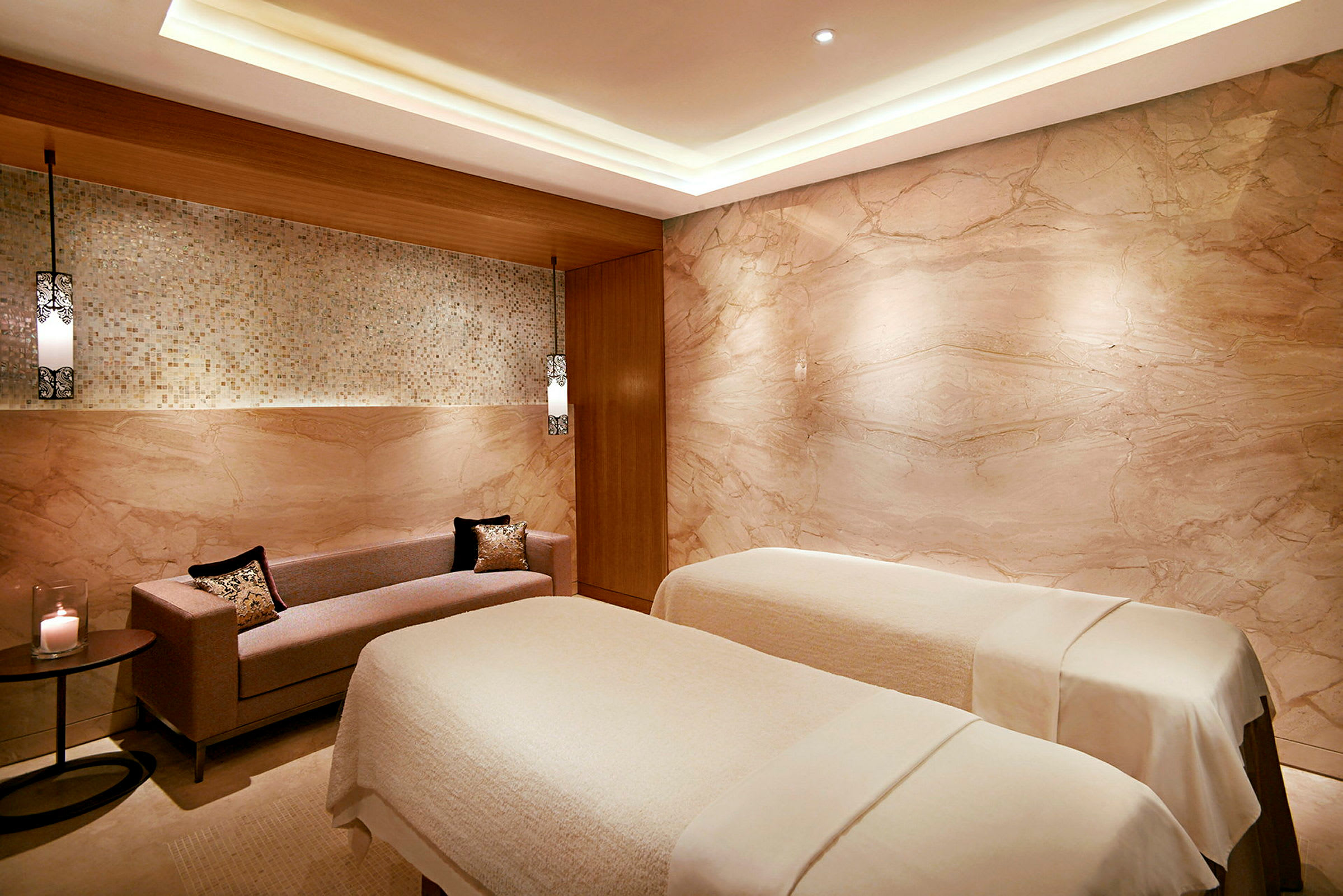 Spa-huone, jossa on kaksi hierontapöytää ja sohva. (Tekoälyn luoma teksti)