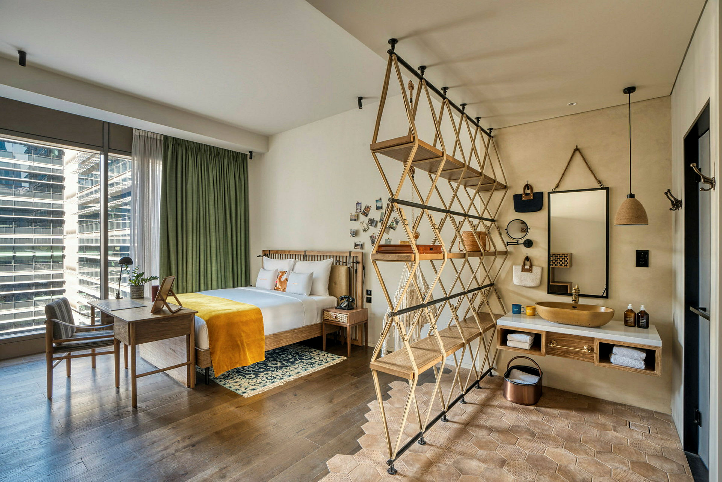 Moderni hotellihuone, jossa sänky, kirjoituspöytä ja avoin kylpyhuoneen suunnittelu. (Tekoälyn luoma teksti)